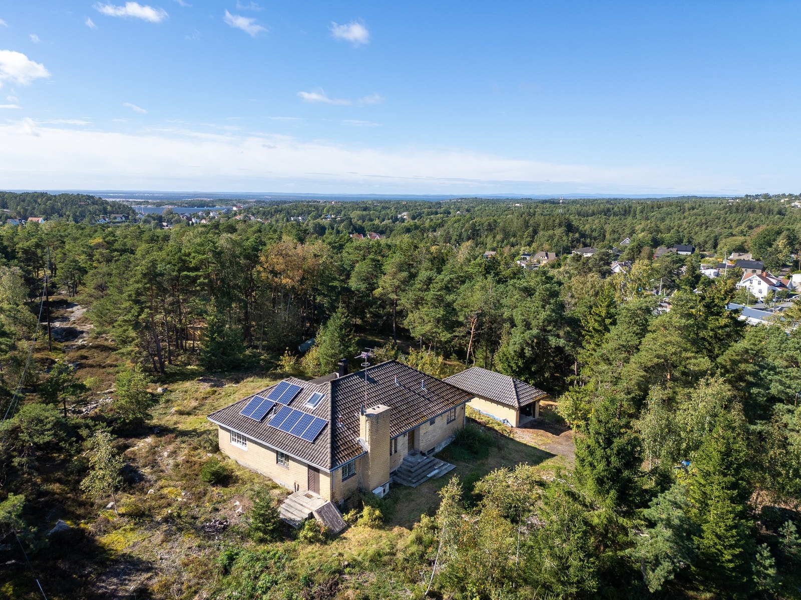 Eiendommen ligger på en liten høyde i terrenget omringet av skog. Galleribilde