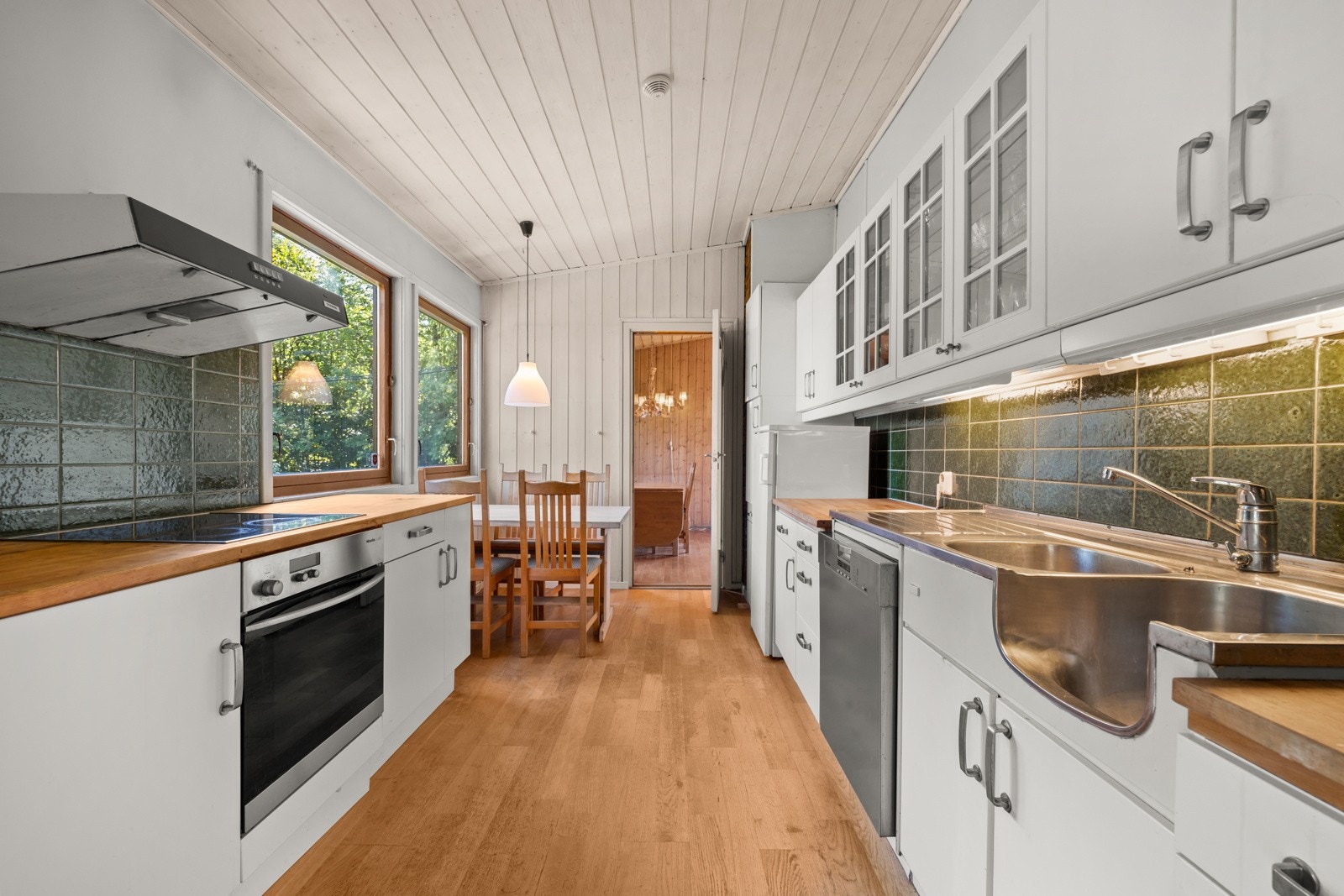 Hvit kjøkkeninnredning med slette fronter og heltre benkeplate. Galleribilde