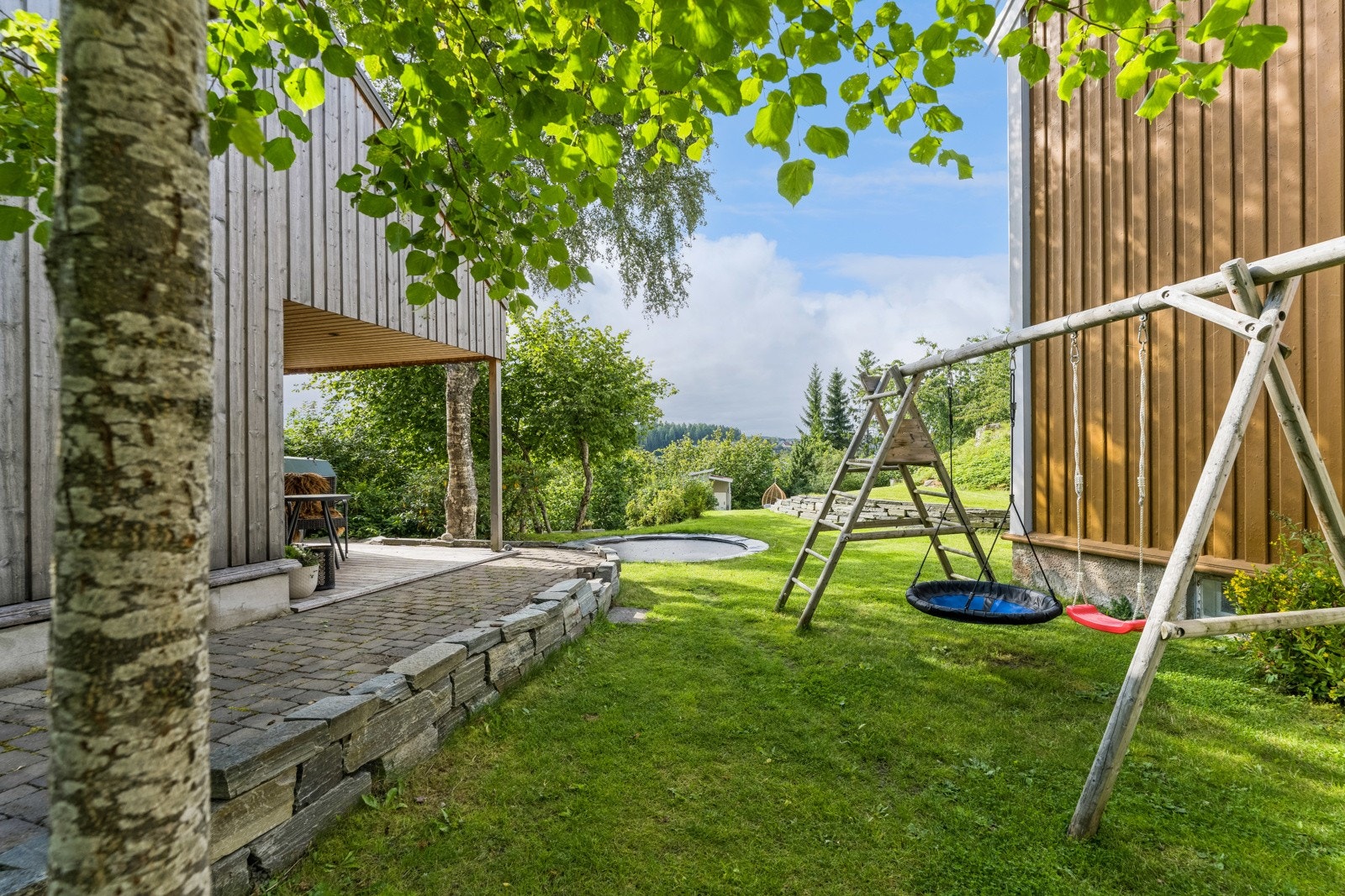 En flott mur av tørrstablet skifer er etablert langs garasjeveggen og ut mot veien. Galleribilde