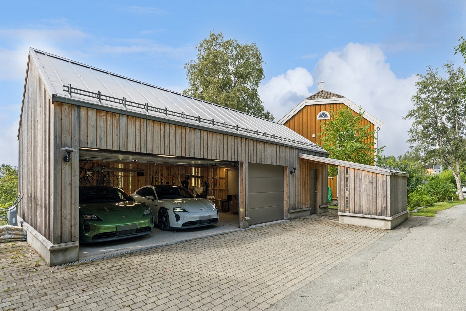 Trippelgarasjen er oppført i vedlikeholdsfri malmfuru. De flotte lampene er PH utendørslamper fra Louis Poulsen. Galleribilde