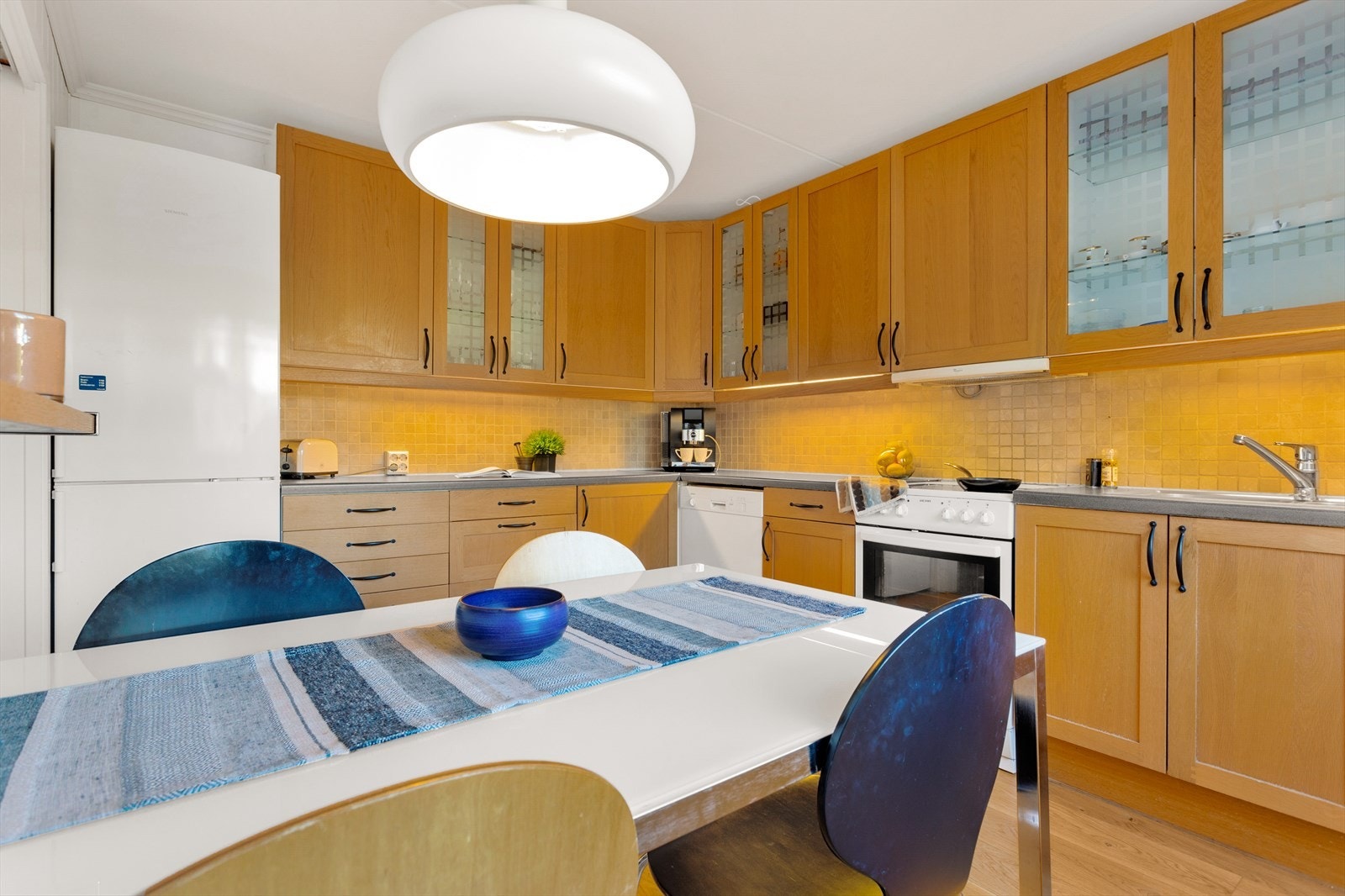 Her finner du profilerte fronter, en laminert benkeplate, fliser mellom skapene, og plass til alle nødvendige hvitevarer. Galleribilde