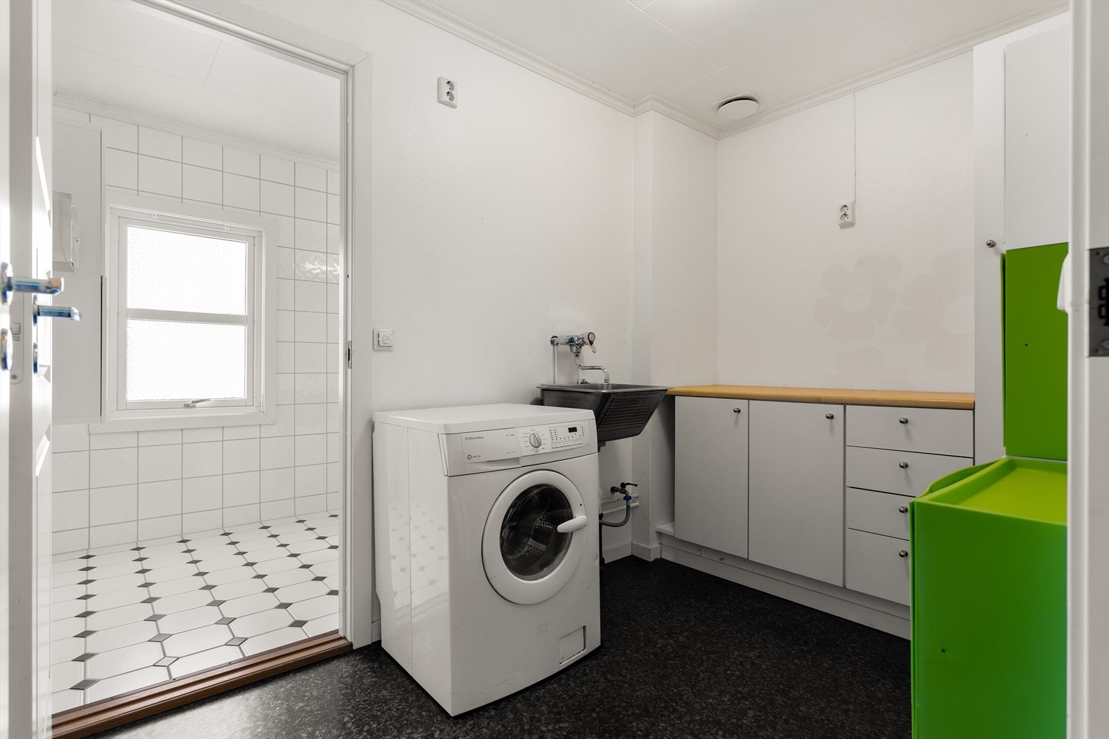 Vaskerom med gulvbelegg fra 2014 og tapetserte vegger. Her er det opplegg for vaskemaskin, samt underskap/sideskap og utslagsvask. I tillegg er det naturlig ventilasjon. Vaskerommet har fått TG3 pga. alder. Galleribilde