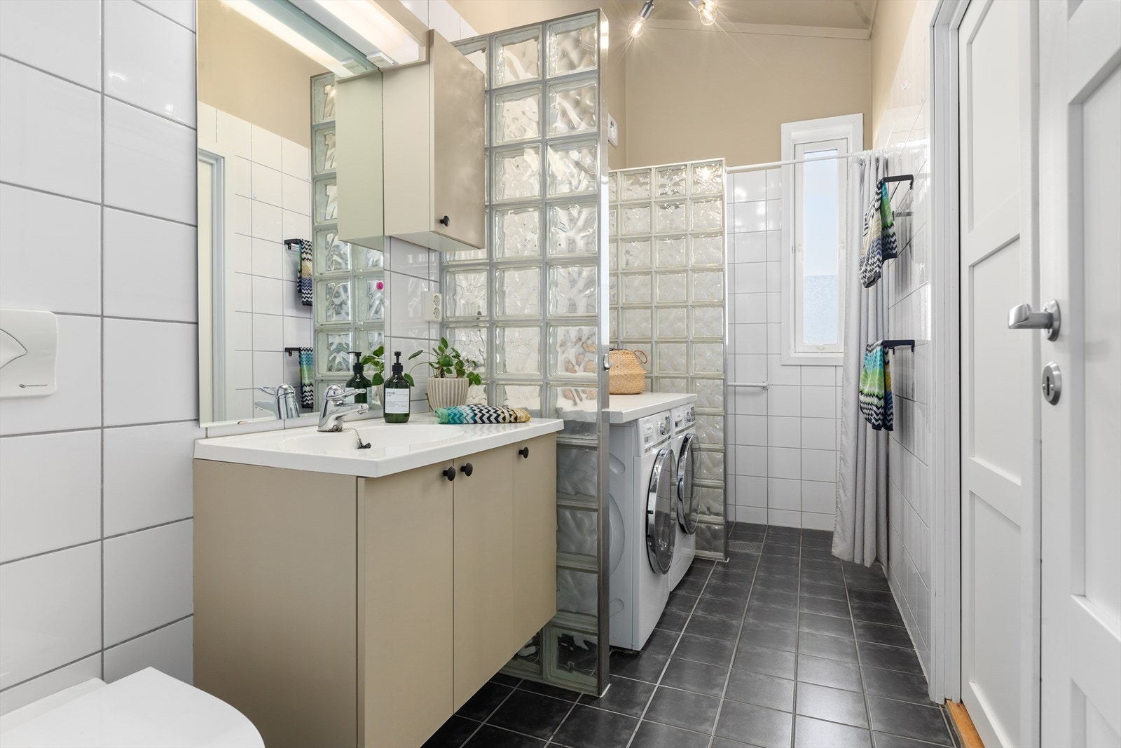 Badet er flislagt med opplegg for vaskemaskin og tørketrommel Galleribilde