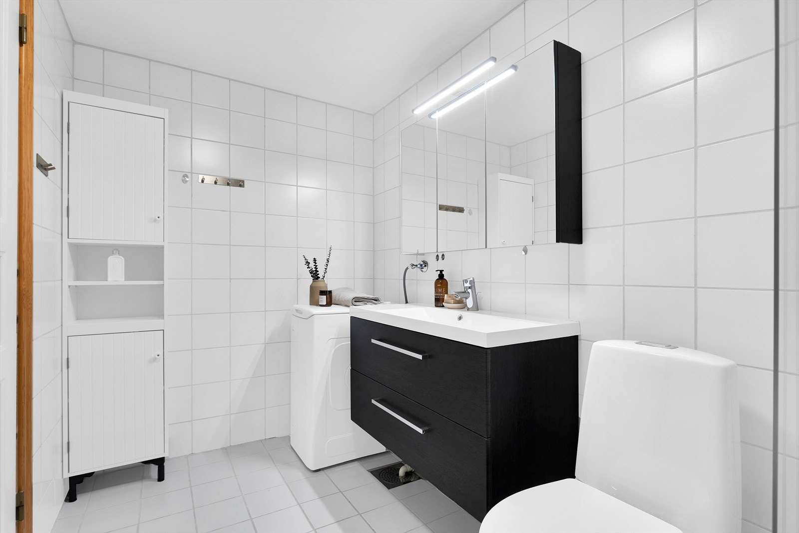 Badet er innredet med moderne baderomsinnredning, speilskap, wc og dusjhjørne Galleribilde