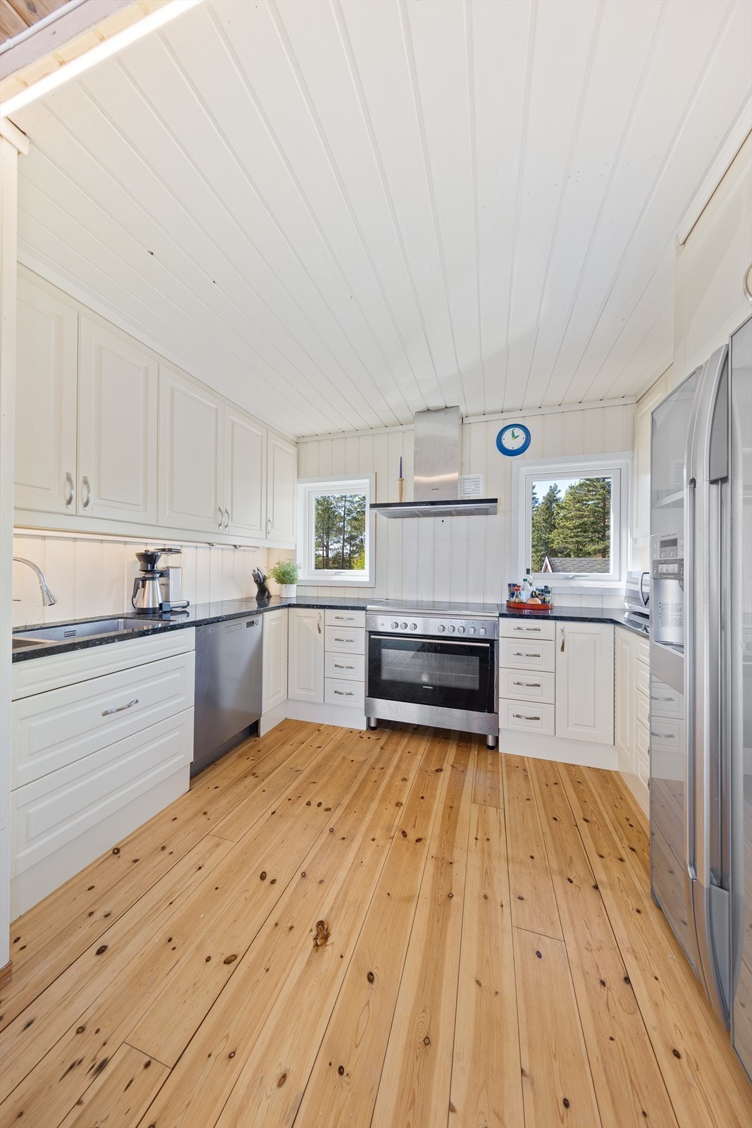 Kjøkkenet har en pen innredning med hvite, profilerte fronter, benkeplate i granitt og frittstående hvitevarer. Galleribilde