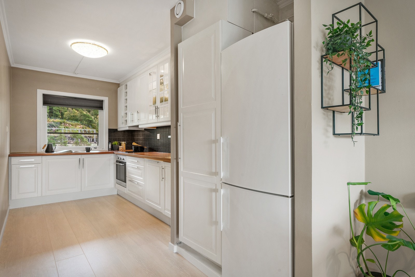 - Leiligheten har et pent IKEA kjøkken med hvite profilerte fronter og flis over laminert benkeplate, med kjøkkenvask i rustfritt stål - Galleribilde