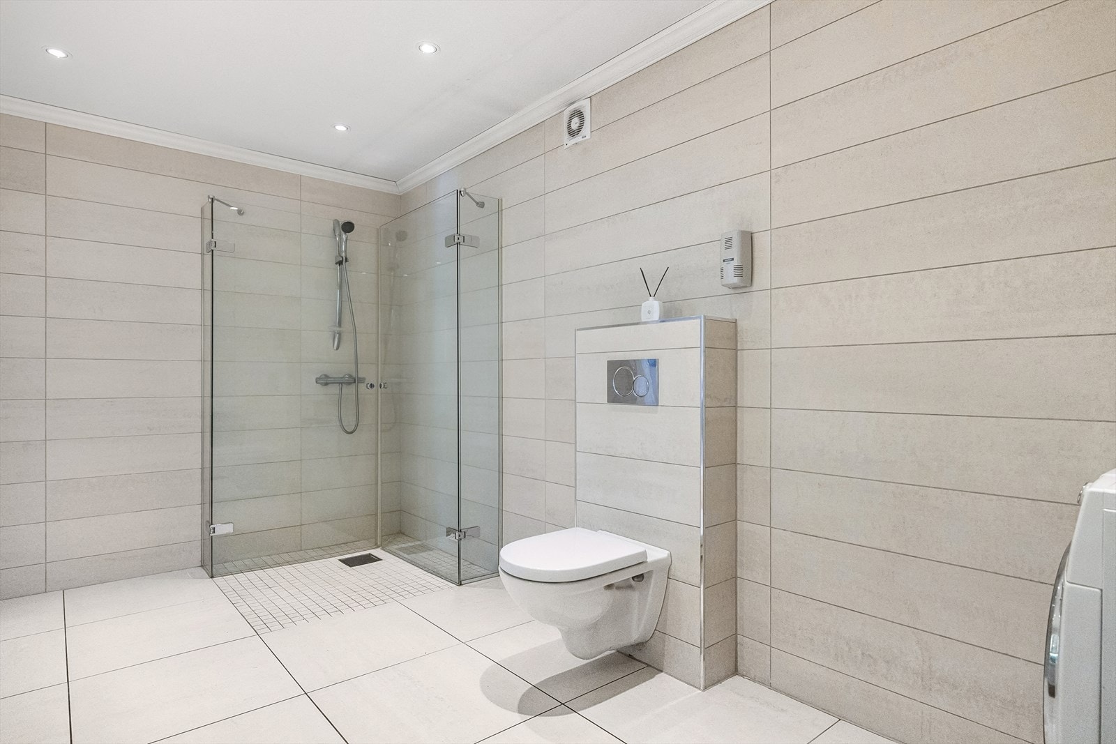 Badet er svært romslig og har moderne fasiliteter med vegghengt toalett, dusjhjørne med glassdører, en moderne servantinnredning og opplegg for vaskemaskin. Galleribilde
