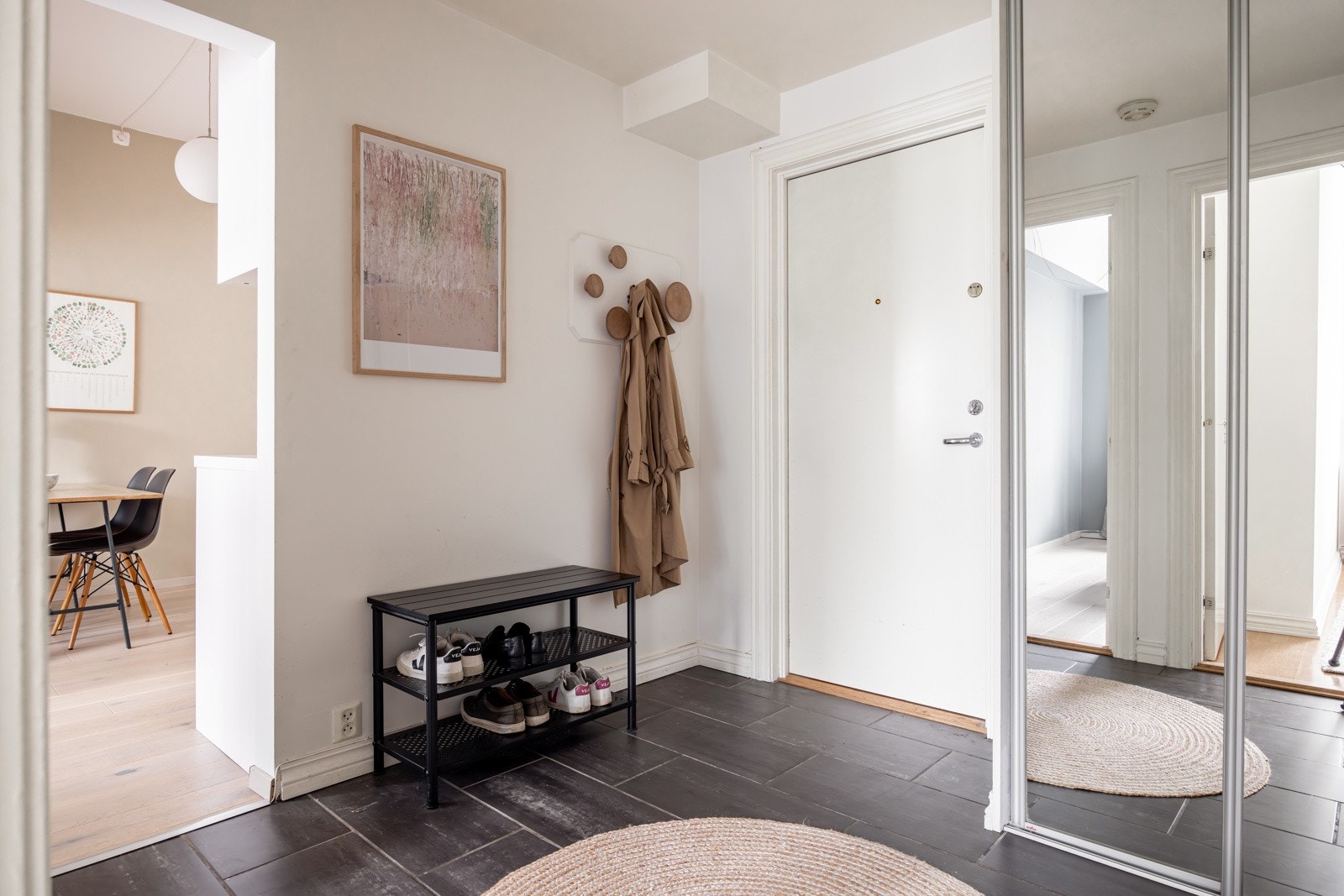 Når du trer inn i leiligheten kommer du inn i en lys og praktisk entré med mørke fliser på gulv og lysmalte overflater. Galleribilde