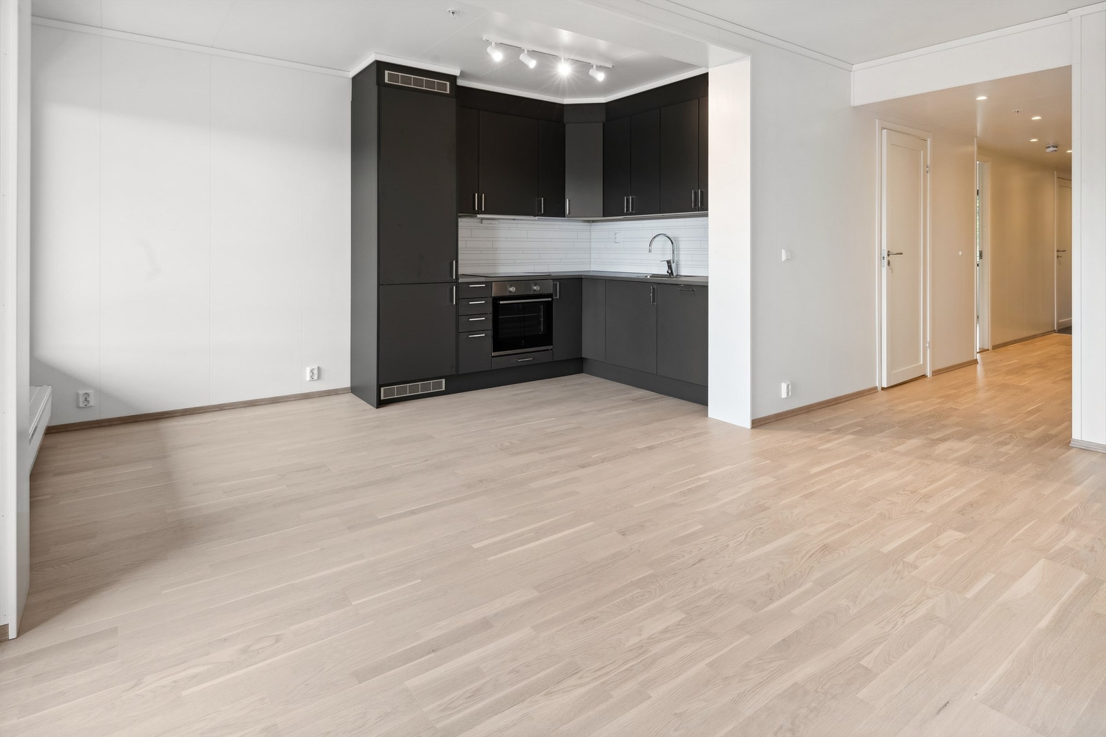 Kjøkkenkrok med integrerte hvitevarer, laminat benkeplate og vannbeskyttende plate mellom over- og underskap. Galleribilde