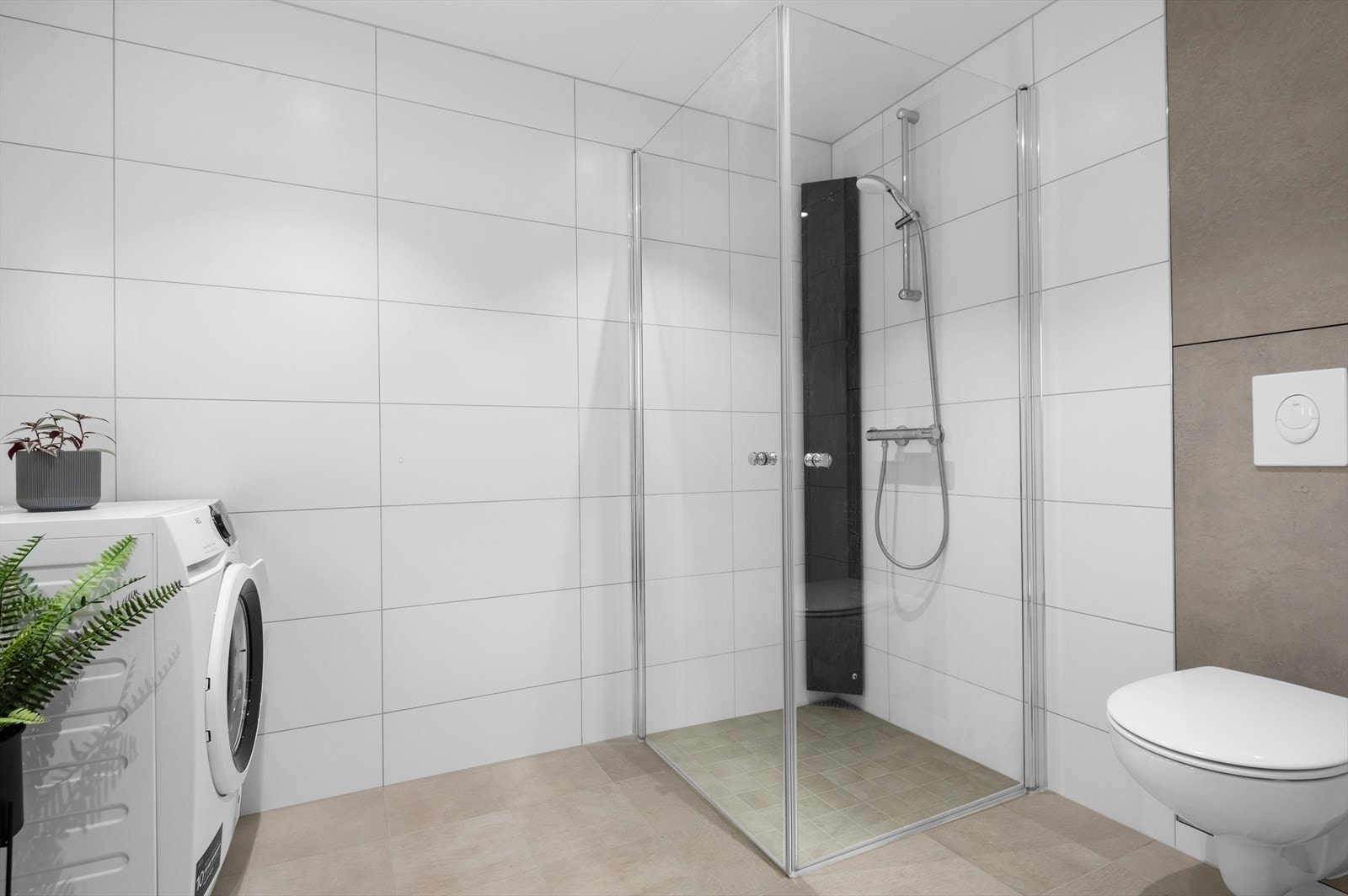 I nedsenket dusjhjørne er det mosaikkfliser på gulvet, og bak vegghengt toalett er det store jordfargede fliser. Galleribilde