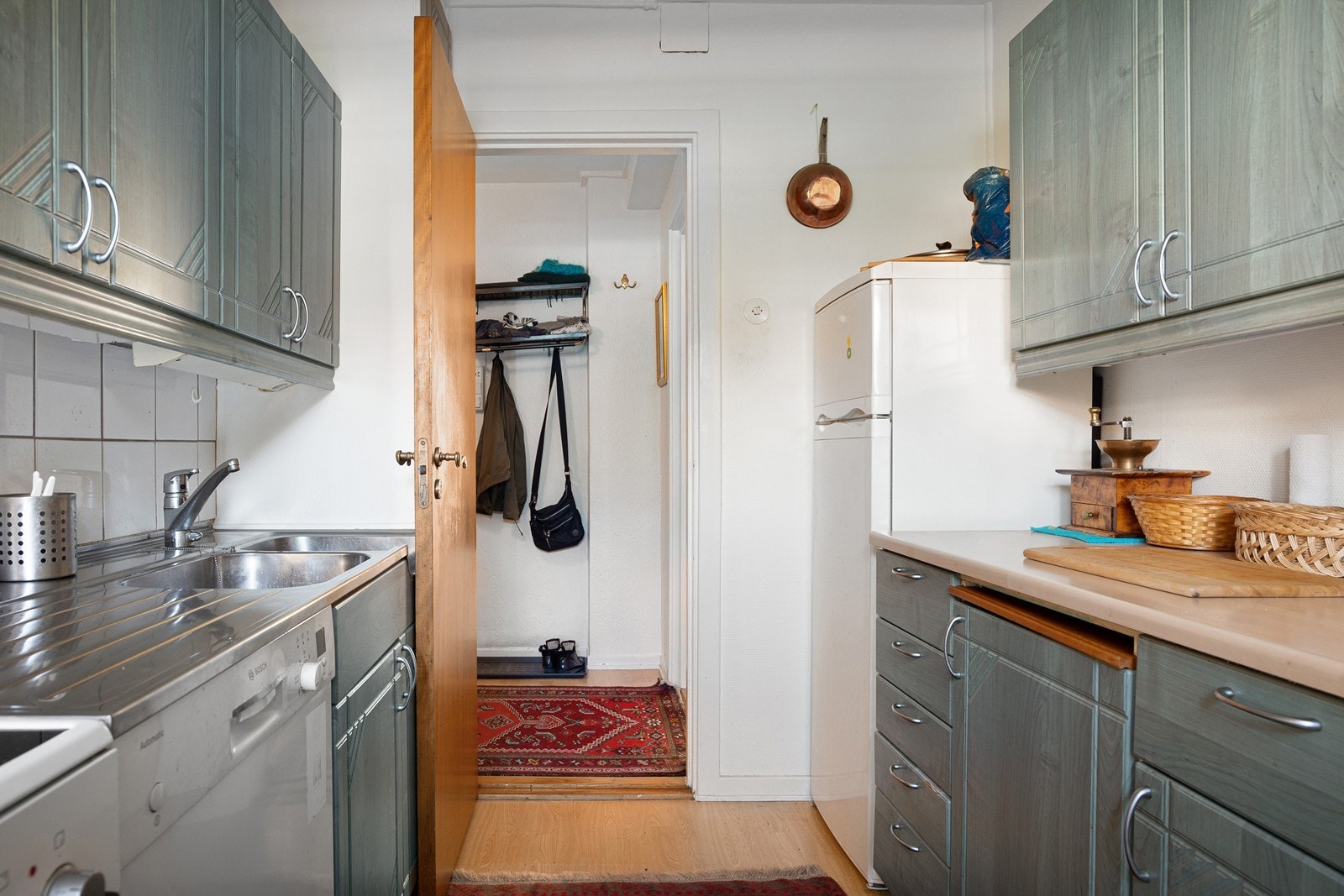 Det er slette fronter og laminert benkeplate med nedfelt oppvaskkum av stål, frittstående komfyr, kjøleskap og oppvaskmaskin Galleribilde