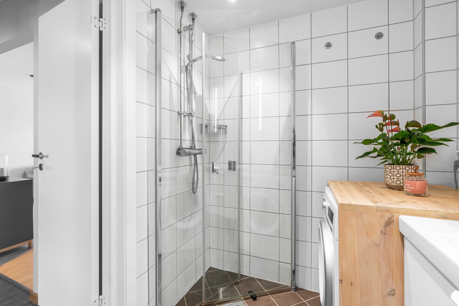 Badet er utstyrt med vegghengt toalett, servant på skuffeseksjon, dobbelt speilskap, og et dusjhjørne med innfellbare glassvegger Galleribilde
