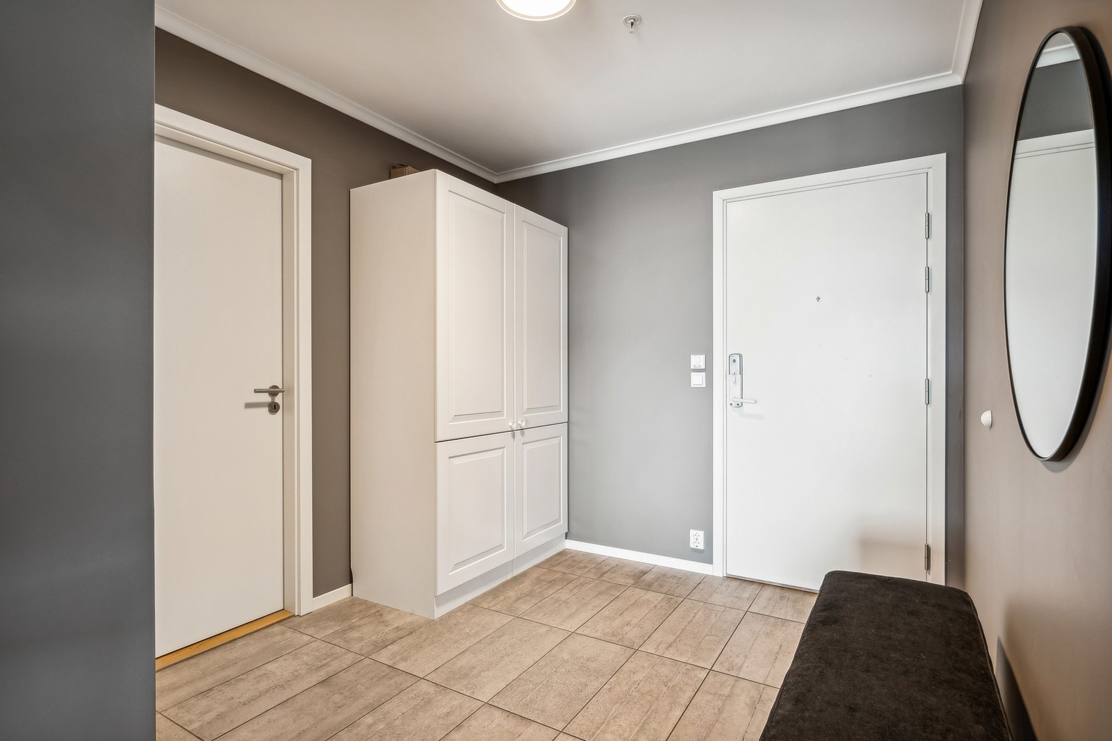 Her kommer du inn i en moderne, flislagt entré med god plass til å hensette sko og annet yttertøy. Galleribilde
