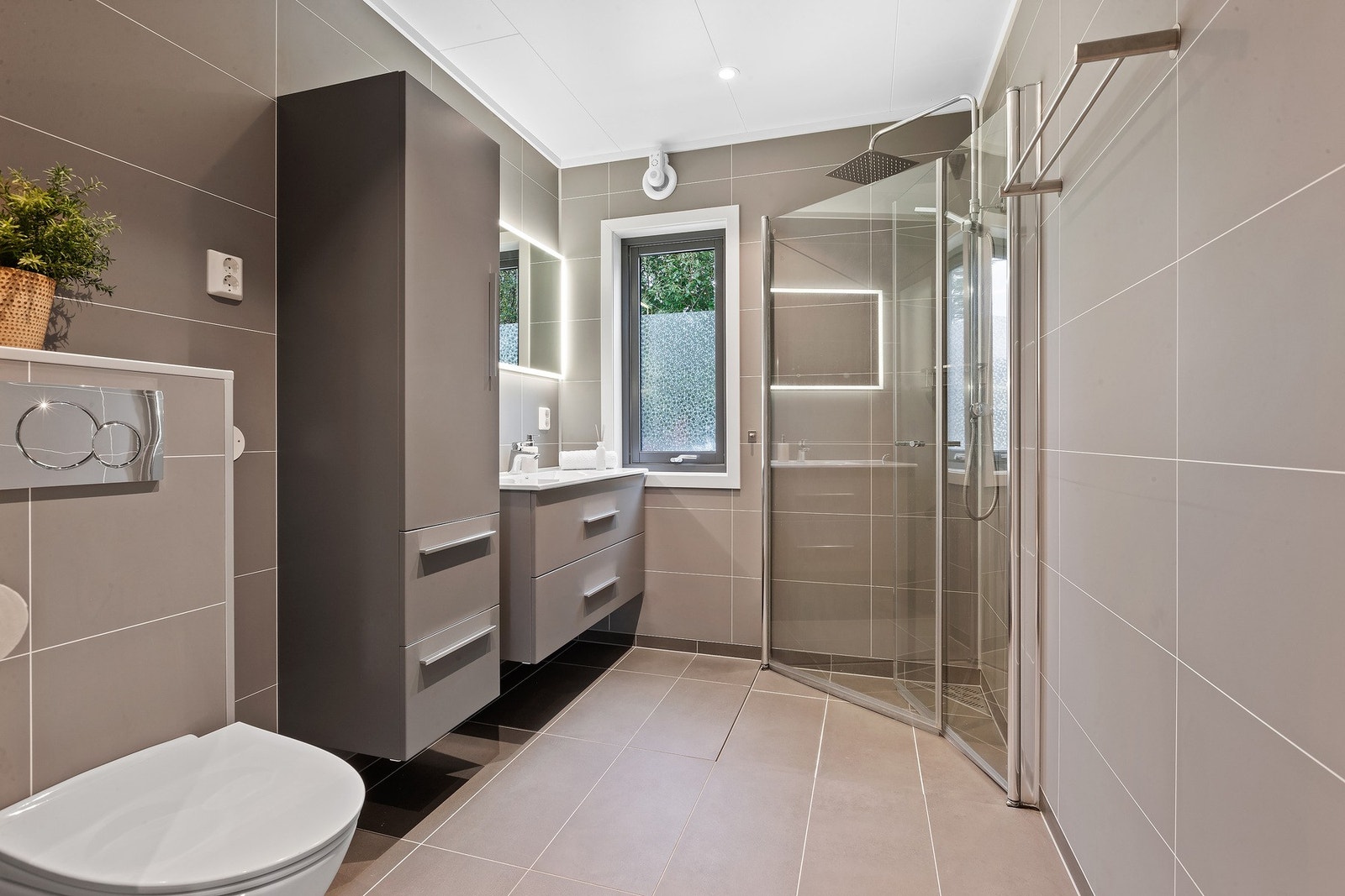 Pent bad med stilren baderomsinnredning med integrert lys i speil. Galleribilde