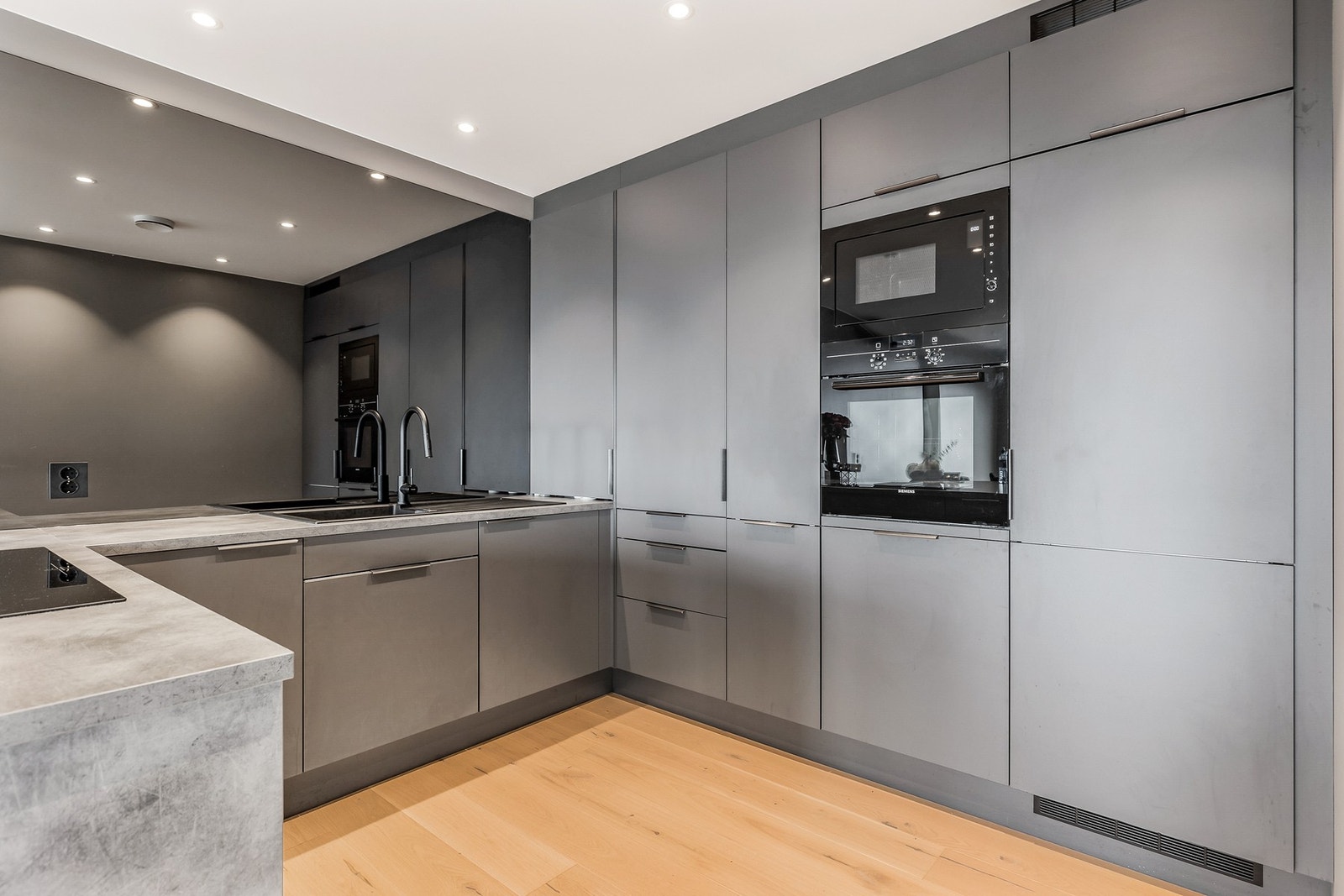 Kjøkken med slette fronter og integrerte hvitevarer som stekovn og micro plassert i annvenlig høyde Galleribilde