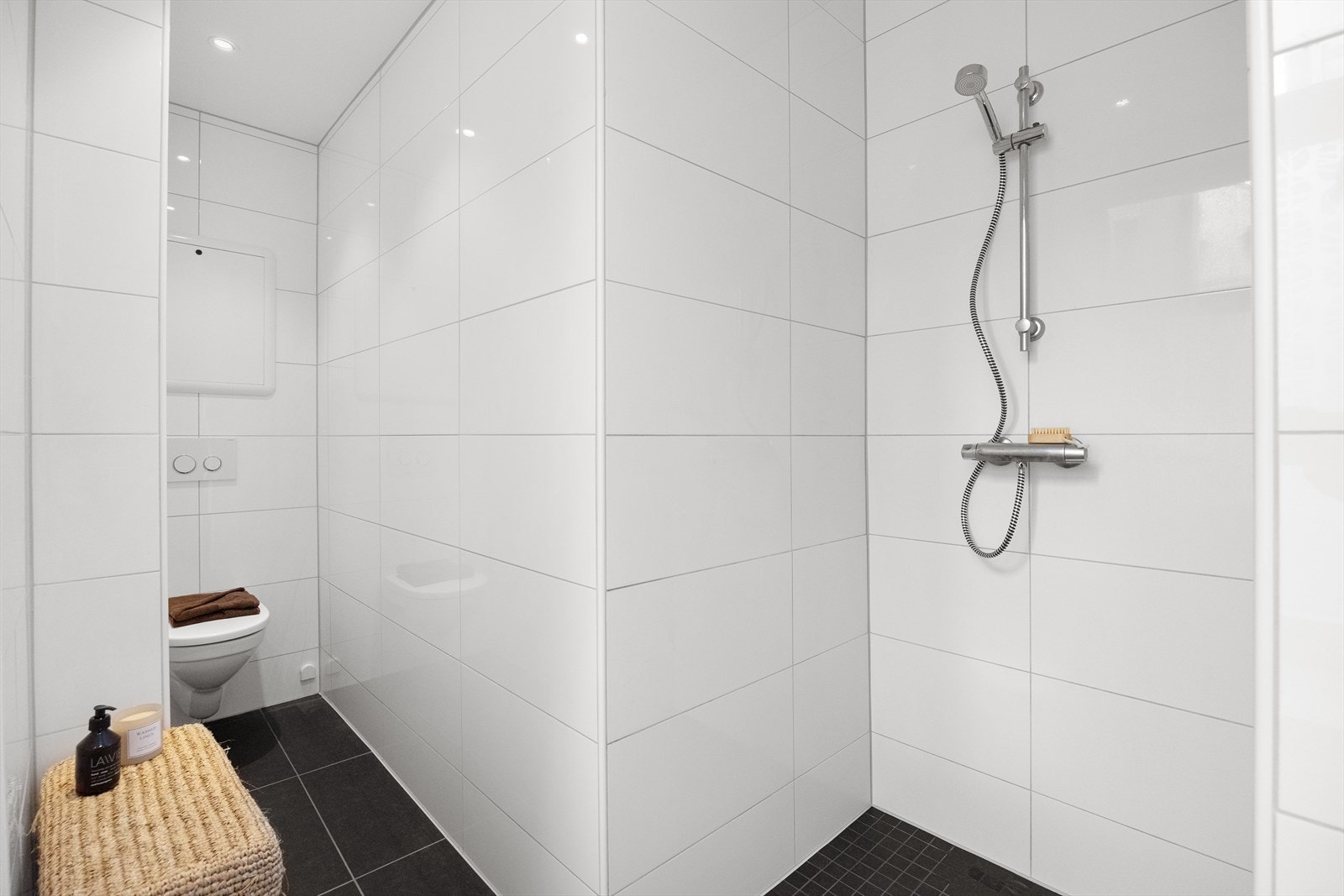Badet er innredet med dusjnisje, servant, møbler, veggmontert wc og opplegg for vaskemaskint Galleribilde