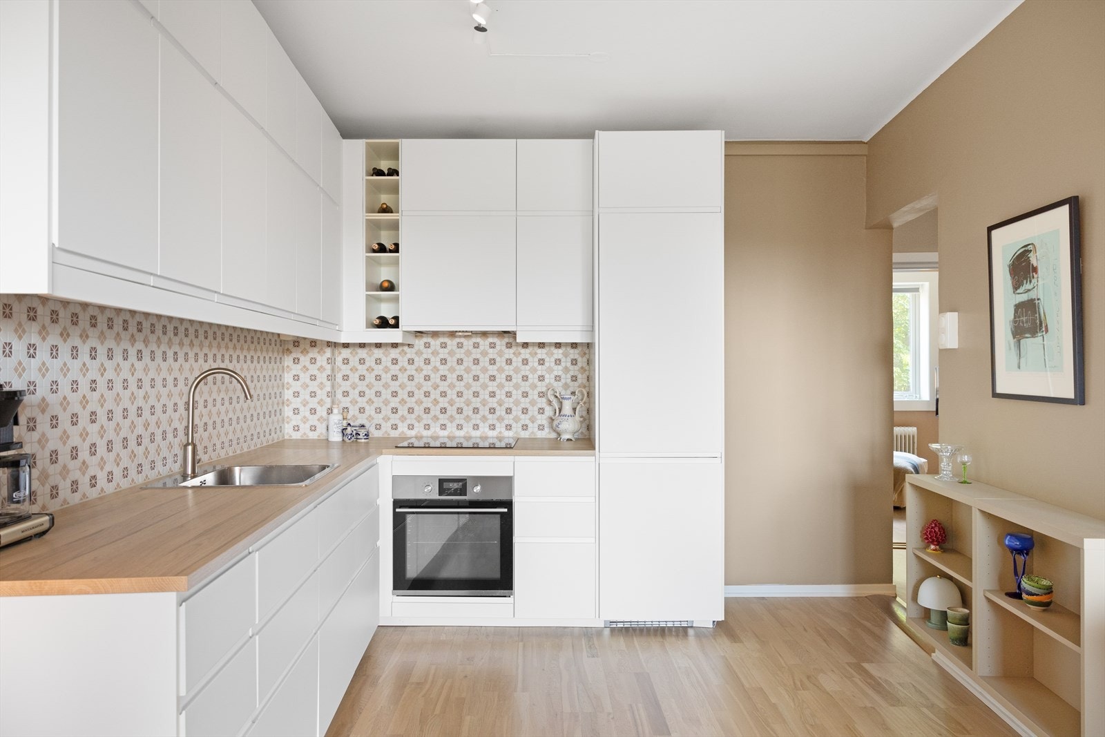 Moderne IKEA-kjøkken fra 2017 med rikelig skap- og benkeplass. Kjøkkenet har hvite, glatte fronter, laminat benkeplate og oppvaskkum i rustfritt stål med ettgreps svingbart blandebatteri. Fliser mellom benkeplate og overskap ble installert i 2023. Galleribilde