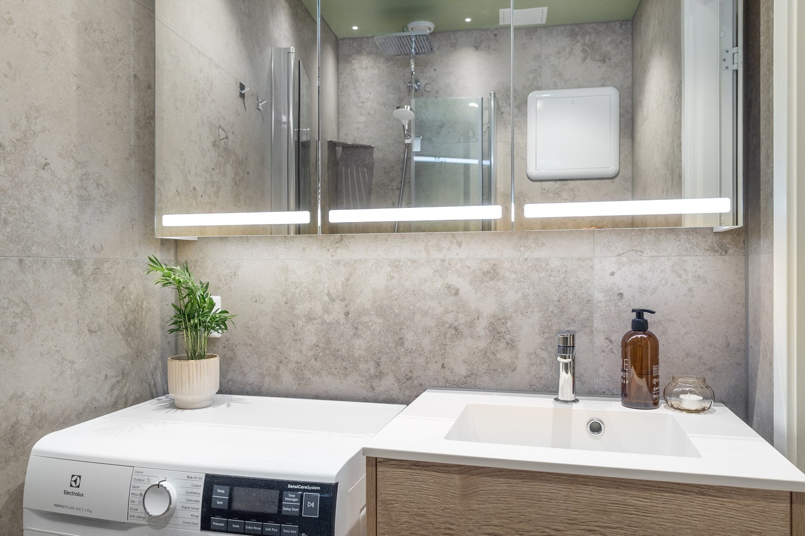 Badet er innredet med servantskap, vegghengt toalett med innebygd sisterne og dusjhjørne med innfellbare glassvegger. Galleribilde