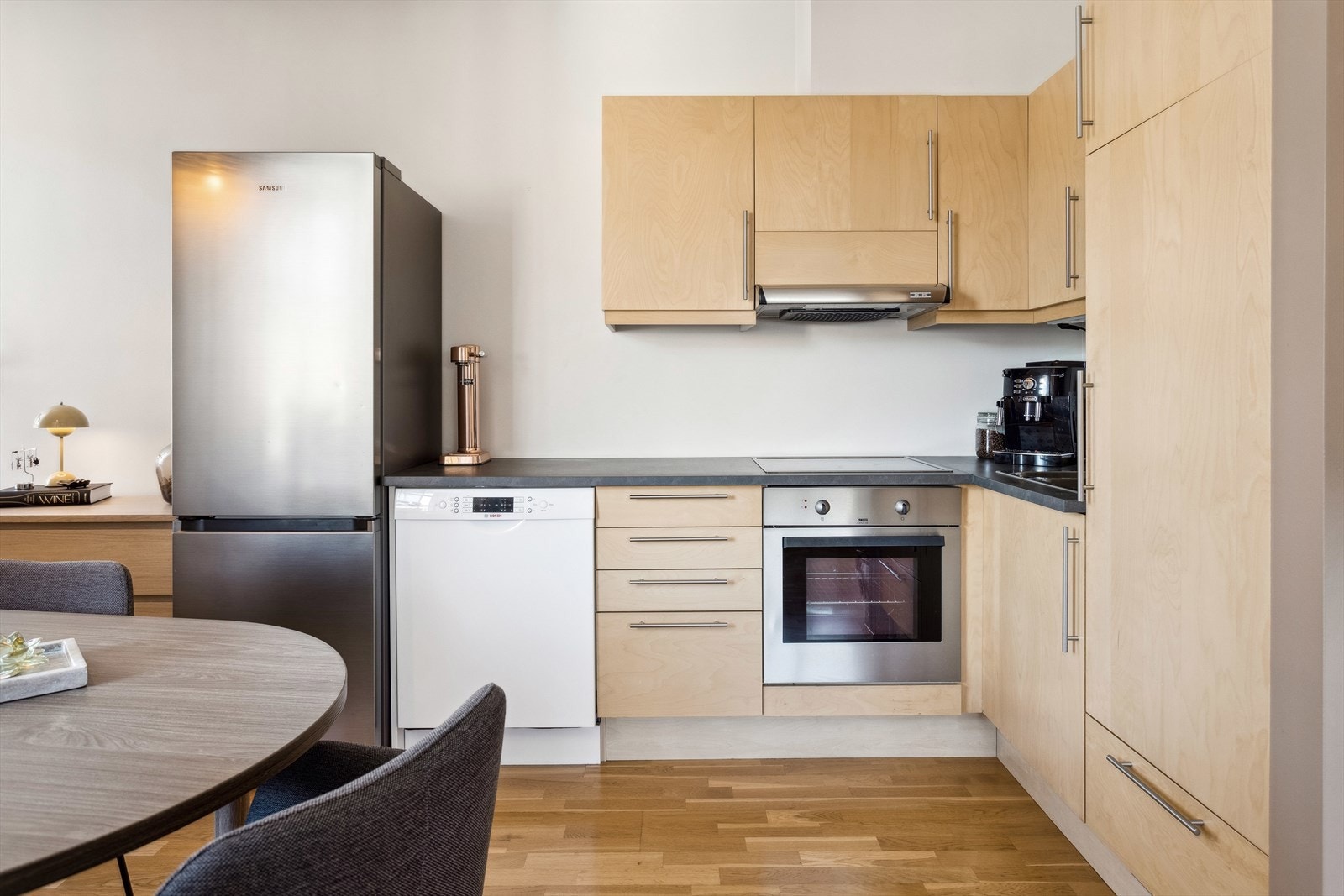 Kjøkkenet inneholder laminert benkeplate, foilerte skrog med slette fronter, stekeovn, platetopp og opplegg til oppvaskmaskin. Galleribilde