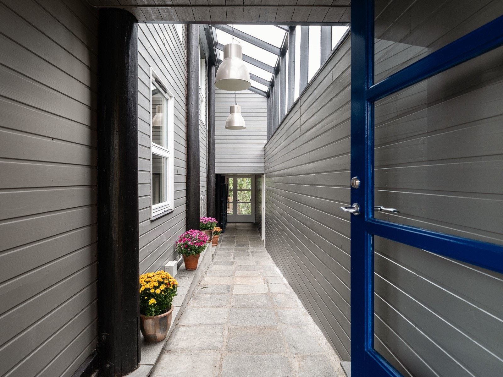 Midt i konstruksjonen har boligen en lukket svalgang med høy himling som tar deg til inngangsdøren på den ene siden og hobbyavdelingen m.m. på den andre Galleribilde