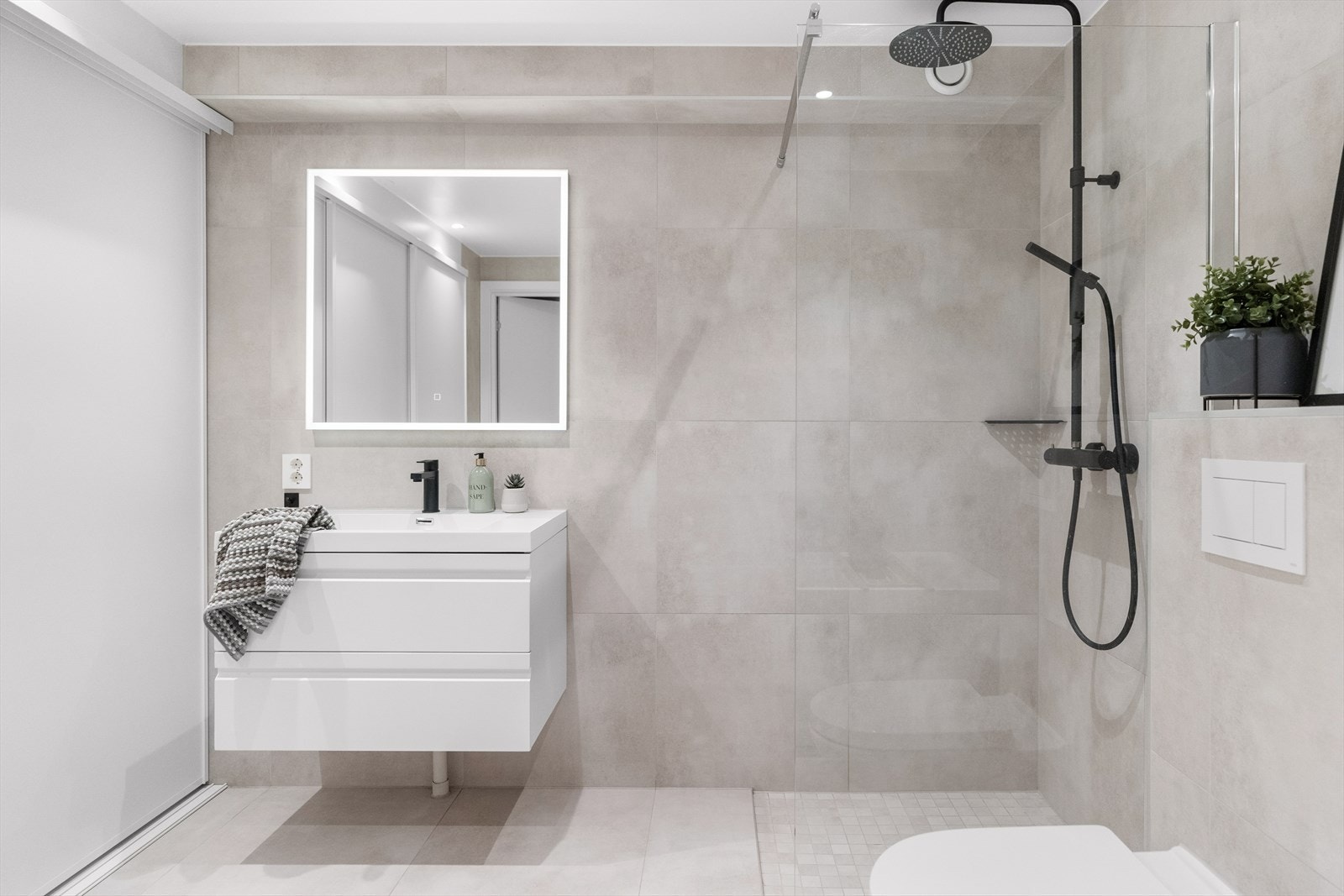 Badet er utstyrt med innredning bestående av nedfelt servant, veggmontert toalett, badekar og dusjvegger/hjørne. Galleribilde