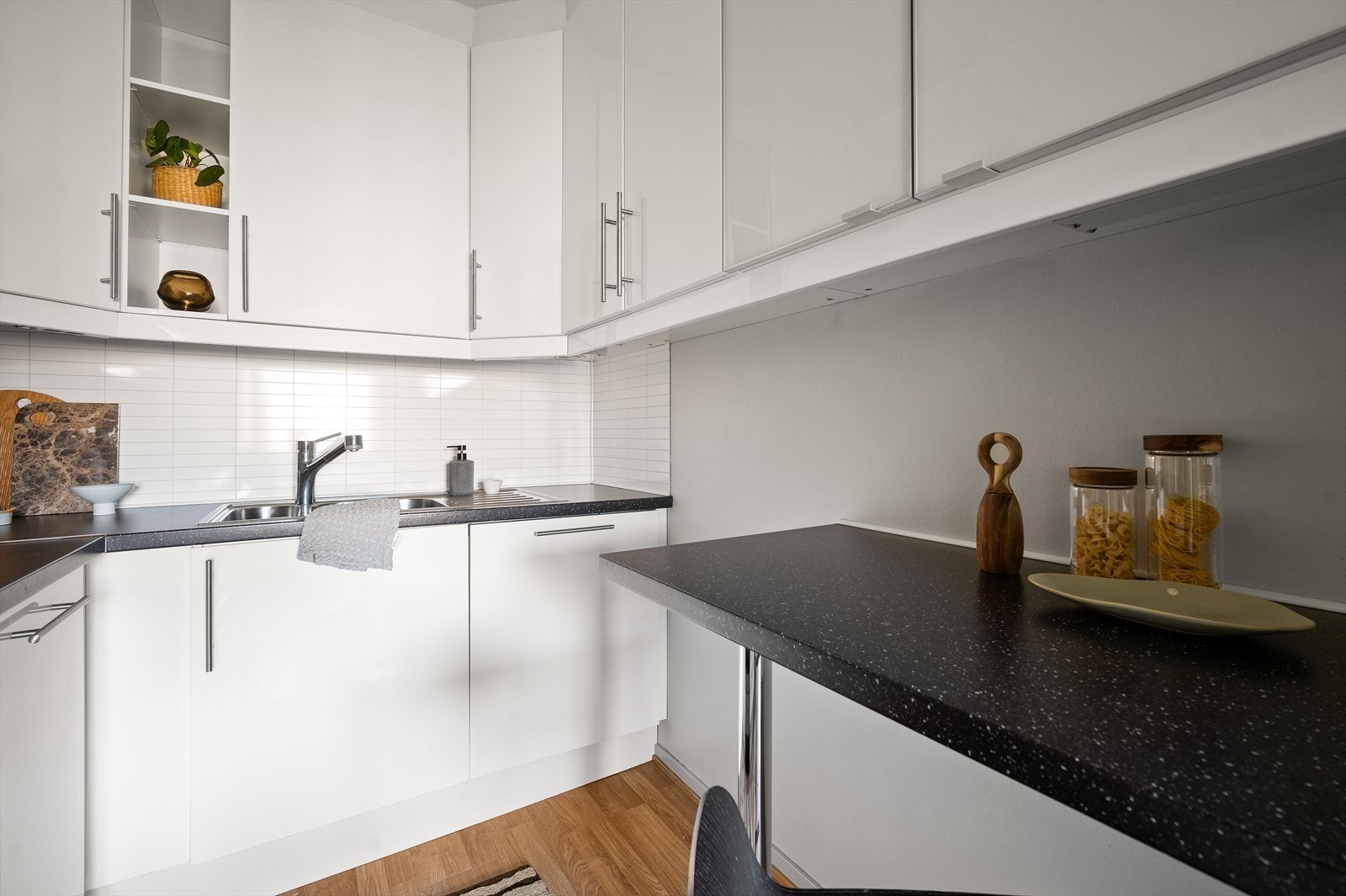 Eldre kjøkkeninnredning fra 2012 med fronter i høyglans, laminat benkeplate, oppvaskkum med kjøkkenplater over benken. Galleribilde