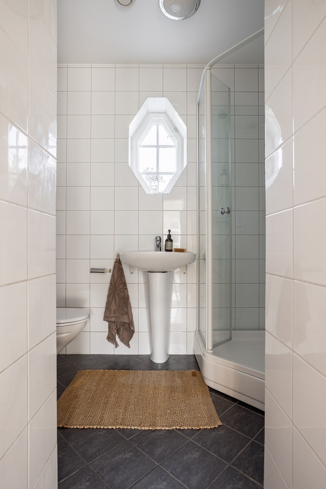 Baderom fra ca. 2005. Badet er utstyrt med vegghengt wc, søyleservant og dusjkabinett. Galleribilde