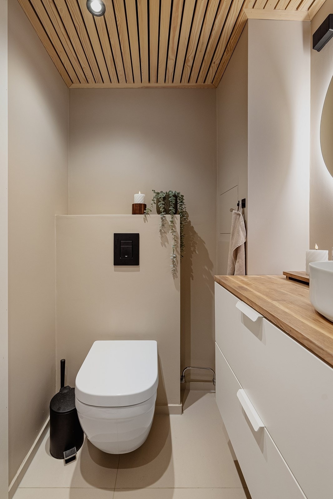 Vegghengt toalett, nedsenket dusjnisje med glassdører, opplegg for oppvaskmaskin. Det er avtrekksvifte i himling som er fuktregulert. Galleribilde