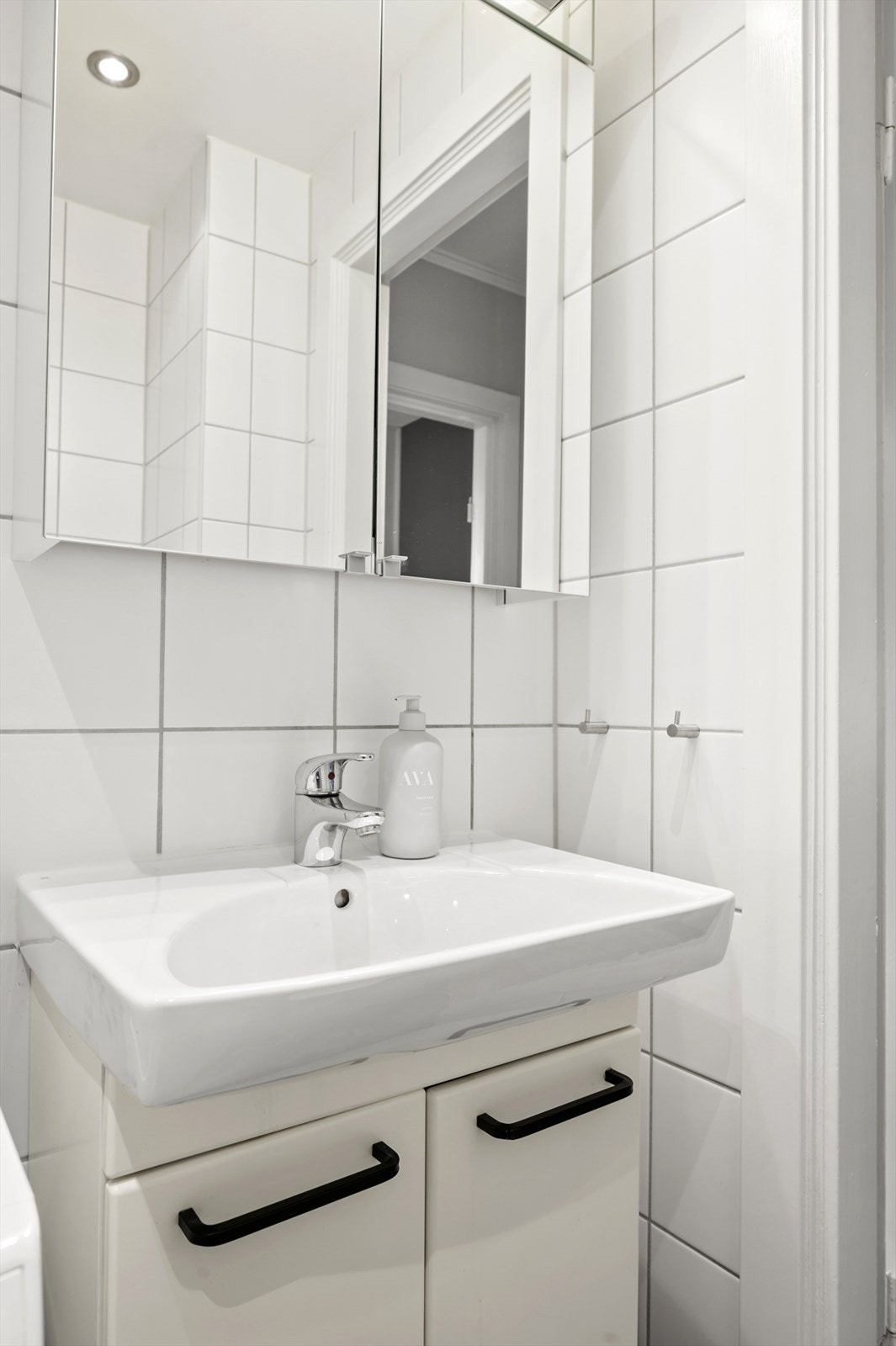 Badet er innredet med gulvstående toalett, servant på vegghengt servantskap, vegghengte dusjdører i glass. Galleribilde