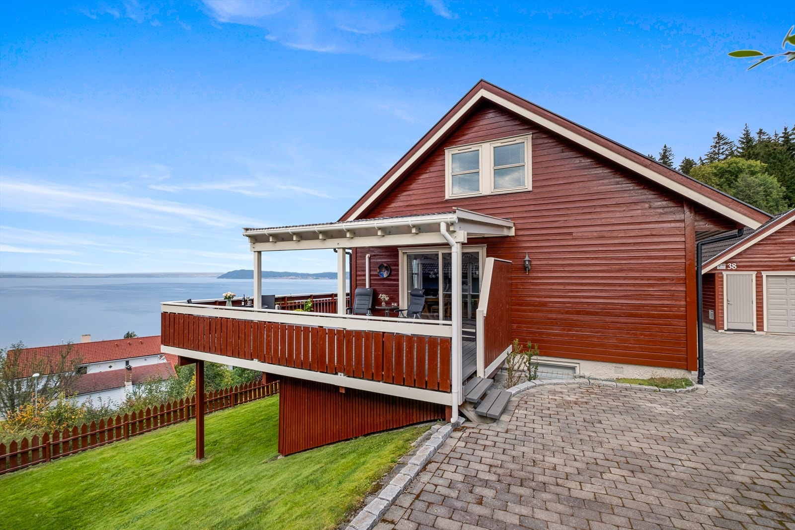Den steinbelagte gårdsplassen går helt inntil den overbygd verandaen med slående utsikt mot Trondheimfjorden Galleribilde