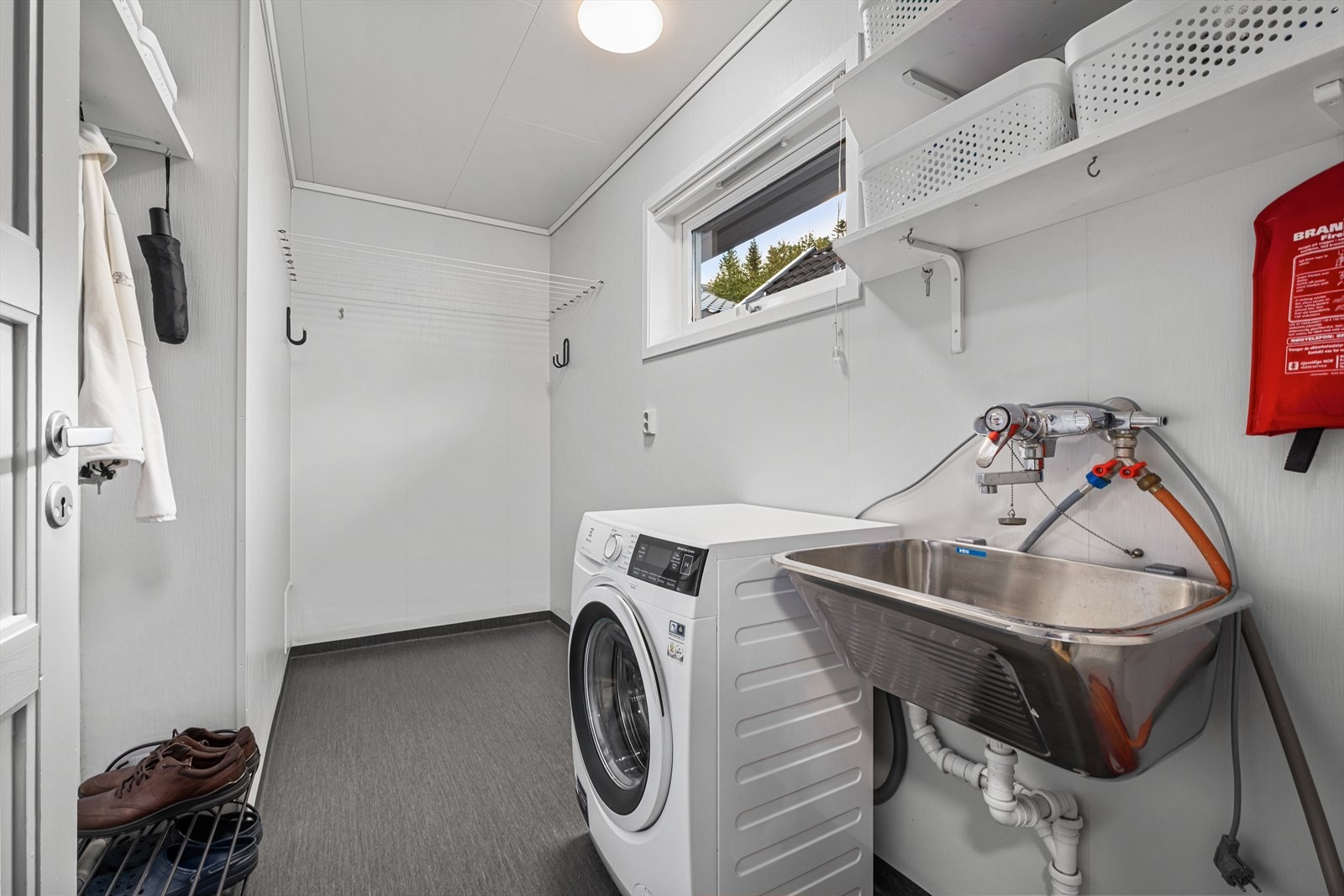 Praktisk beliggende vaskerom utstyrt med opplegg for vaskemaskin, skyllekum og mekanisk avtrekksvifte. Galleribilde