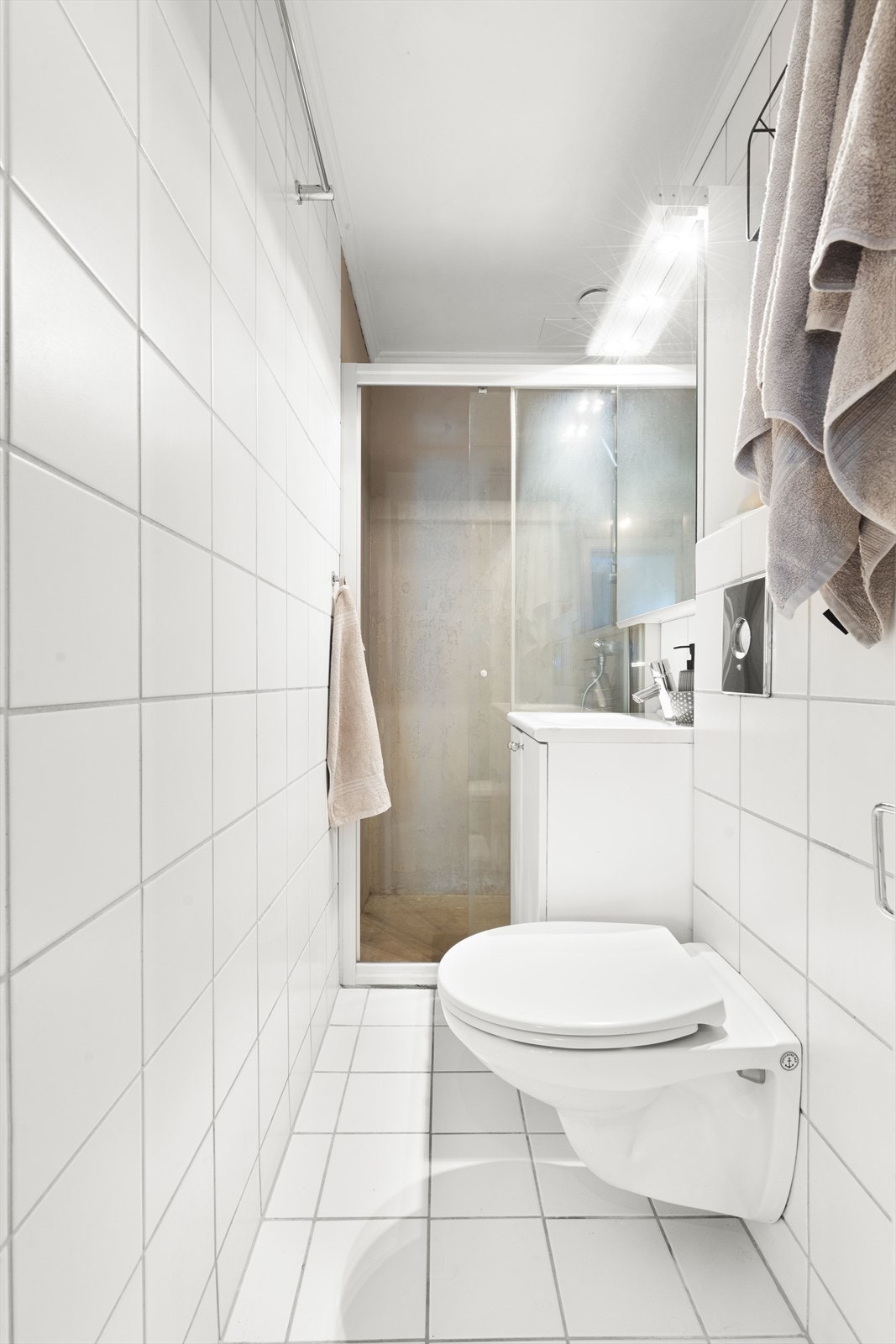 Delikat bad bestående av gulv og vegger med delvis flislagte overflater. Baderomsinnredningen består av benkeskap, veggskap med speilfronter og belysning over servant. Galleribilde