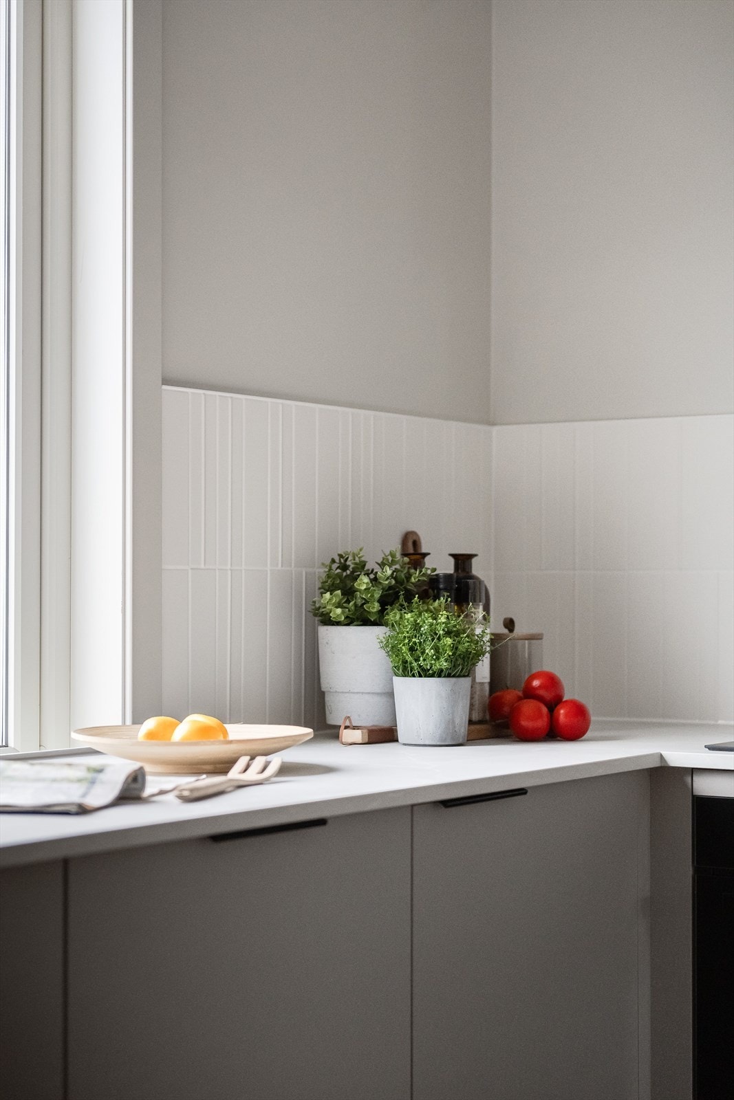 Både fint og praktisk med lyse delikate fliser i benkeryggen. Et stort vindu sørger for naturlig arbeidslys til kjøkkenbenken. Galleribilde