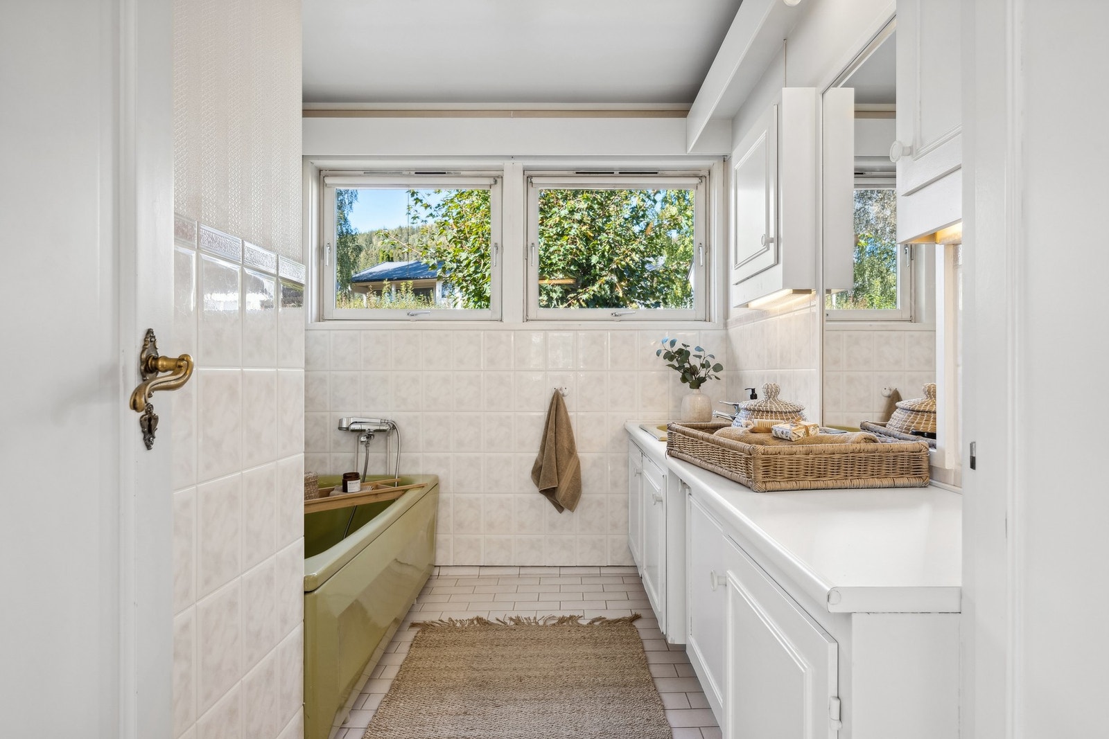 Eldre flislagt bad med badekar og fin plass til oppbevaring i badets innredning. Galleribilde