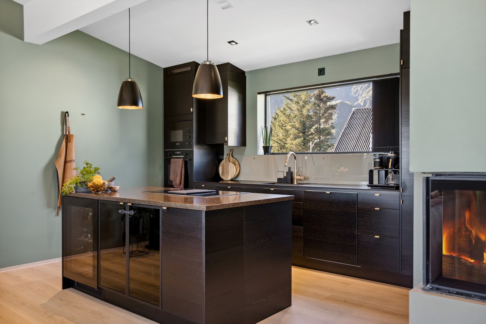 Moderne kjøkken med integrerte hvitevarer og vinkjøler. Benkeplaten på kjøkkenøya er av stein med brun marmor. Galleribilde