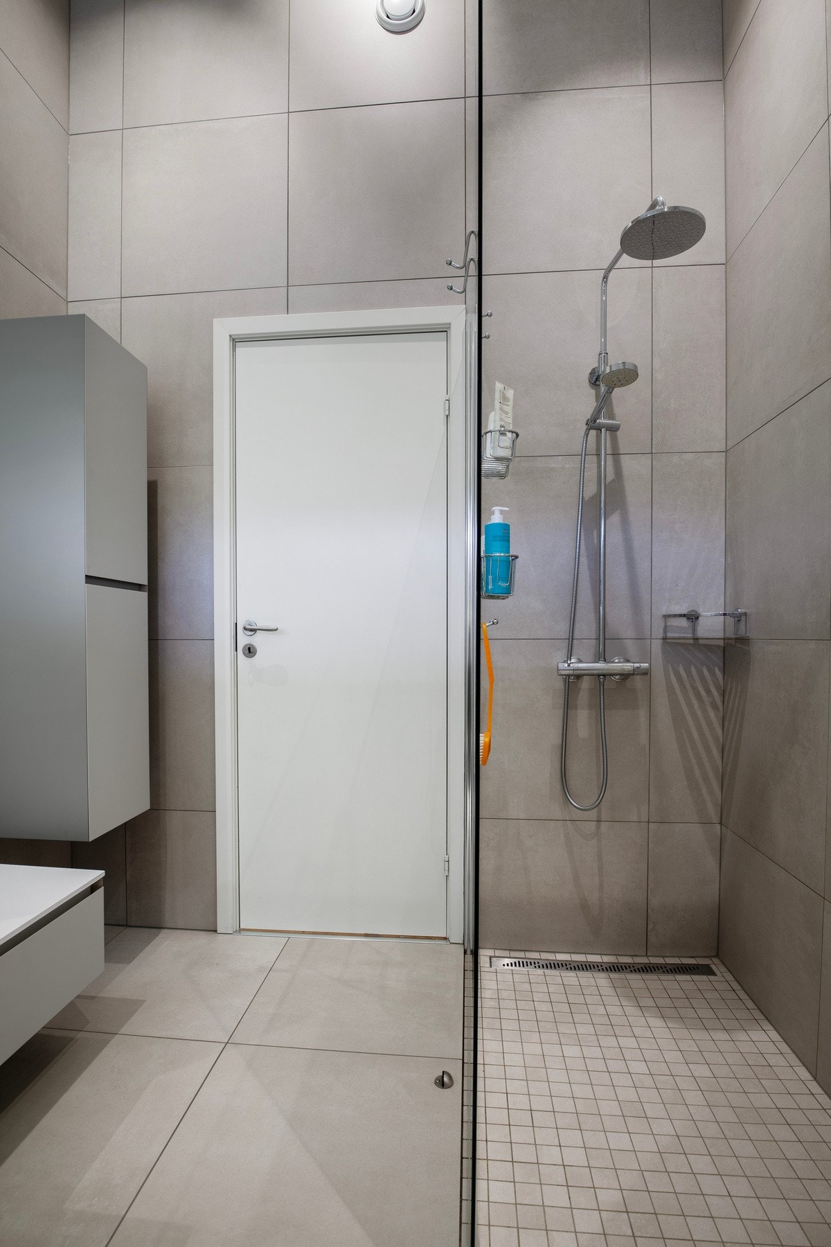 Rommet har innredning med nedfelt servant, veggmontert toalett og dusjvegg med garnityr på vegg. Galleribilde