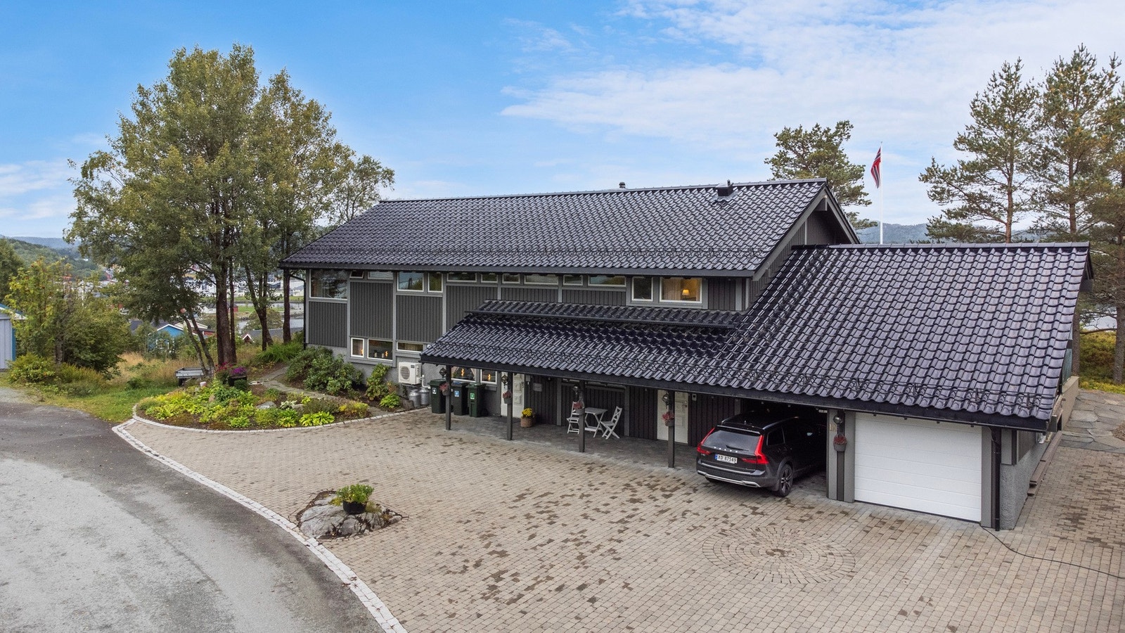 Steinbelagt gårdsplass med carport og garasje. Galleribilde