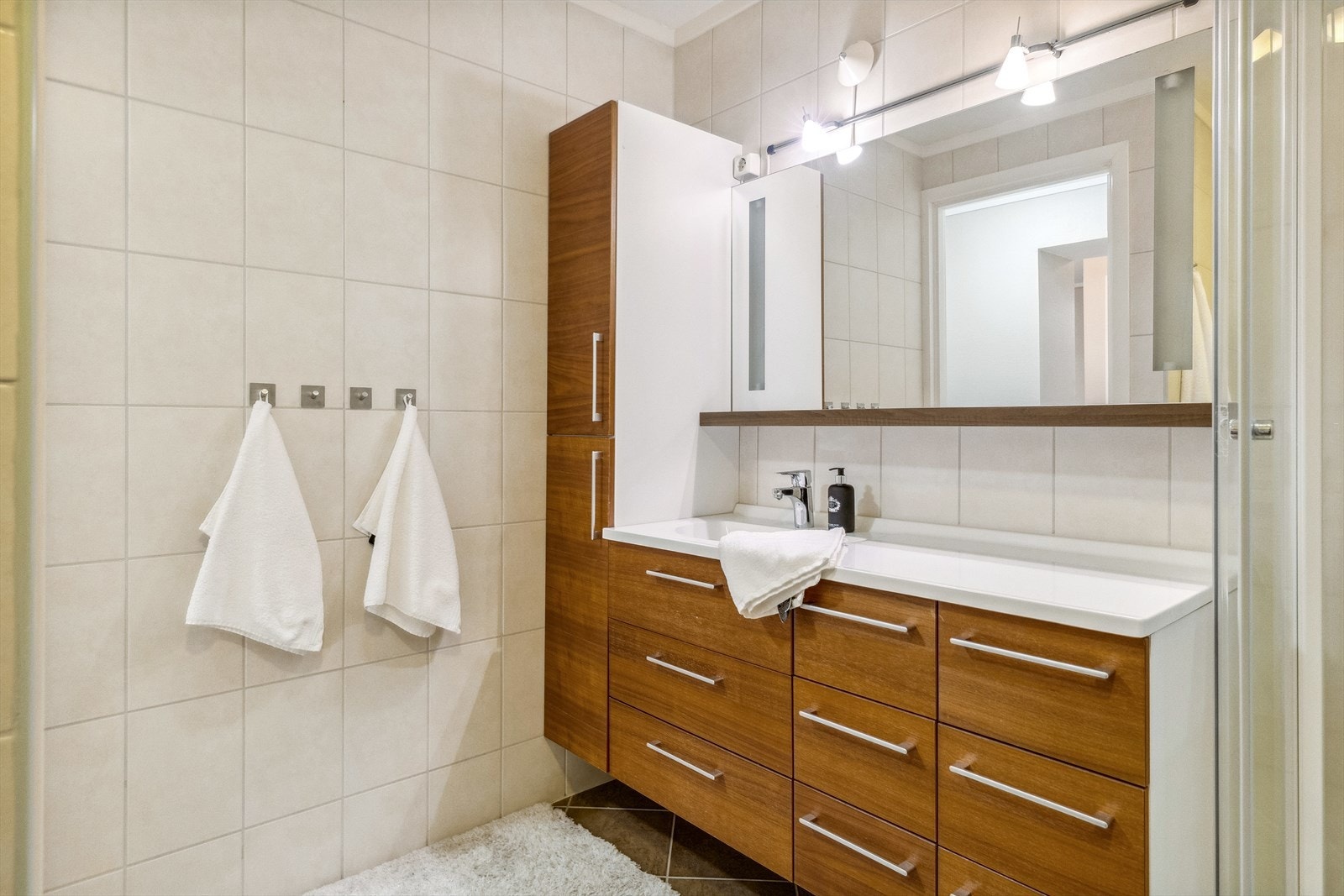 Baderomsinnredningen har god oppbevaringsplass bak brune, glatte fronter på skuffer og høyskap Galleribilde