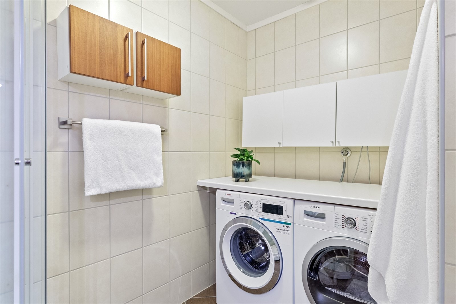 På badet er det også en praktisk vaskeromssone med plass til både vaskemaskin og tørketrommel under benkeplate. Galleribilde