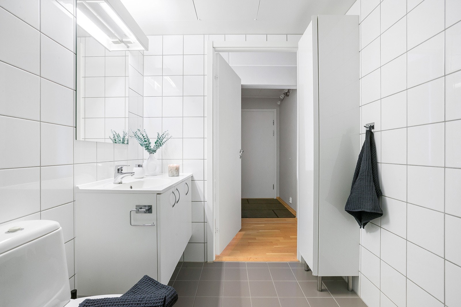 Baderomsinnredningen er bestående av servant med underskap, speil, gulvmontert wc, dusjhjørne med svingbare glassdører og opplegg for vaskemaskin. Galleribilde