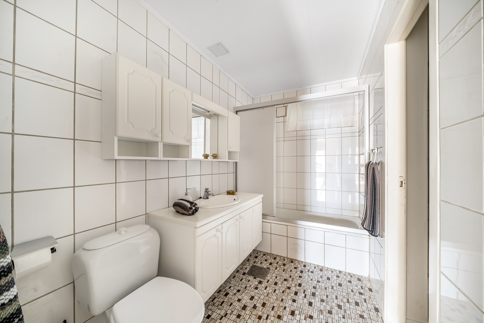 Bad i kjelleren i tilknytning til soverommene. Badet har fliser på gulv og vegger. Rommet er innredet med baderomsinnredning, toalett og badekar med dusjløsning. Galleribilde