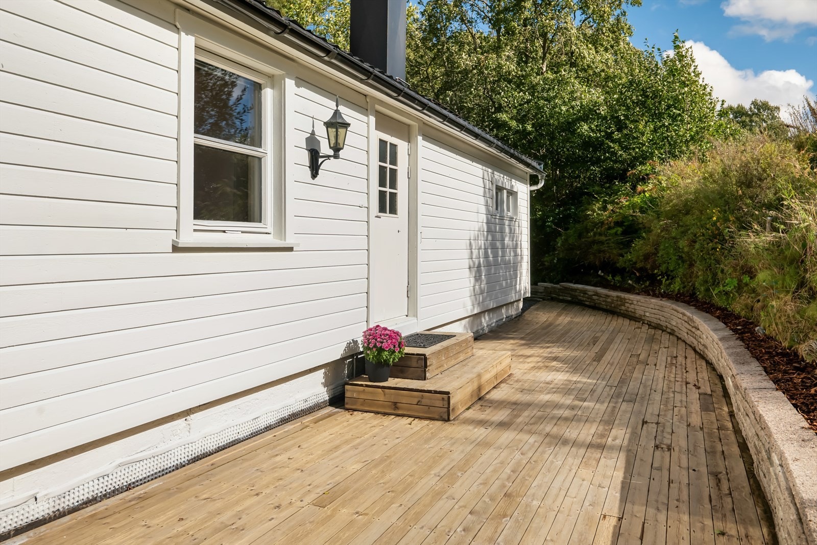 Romslig inngangsparti med terrasseplatting på 24 kvm laget i treverk med trykkimpregnert terrassebord. Galleribilde
