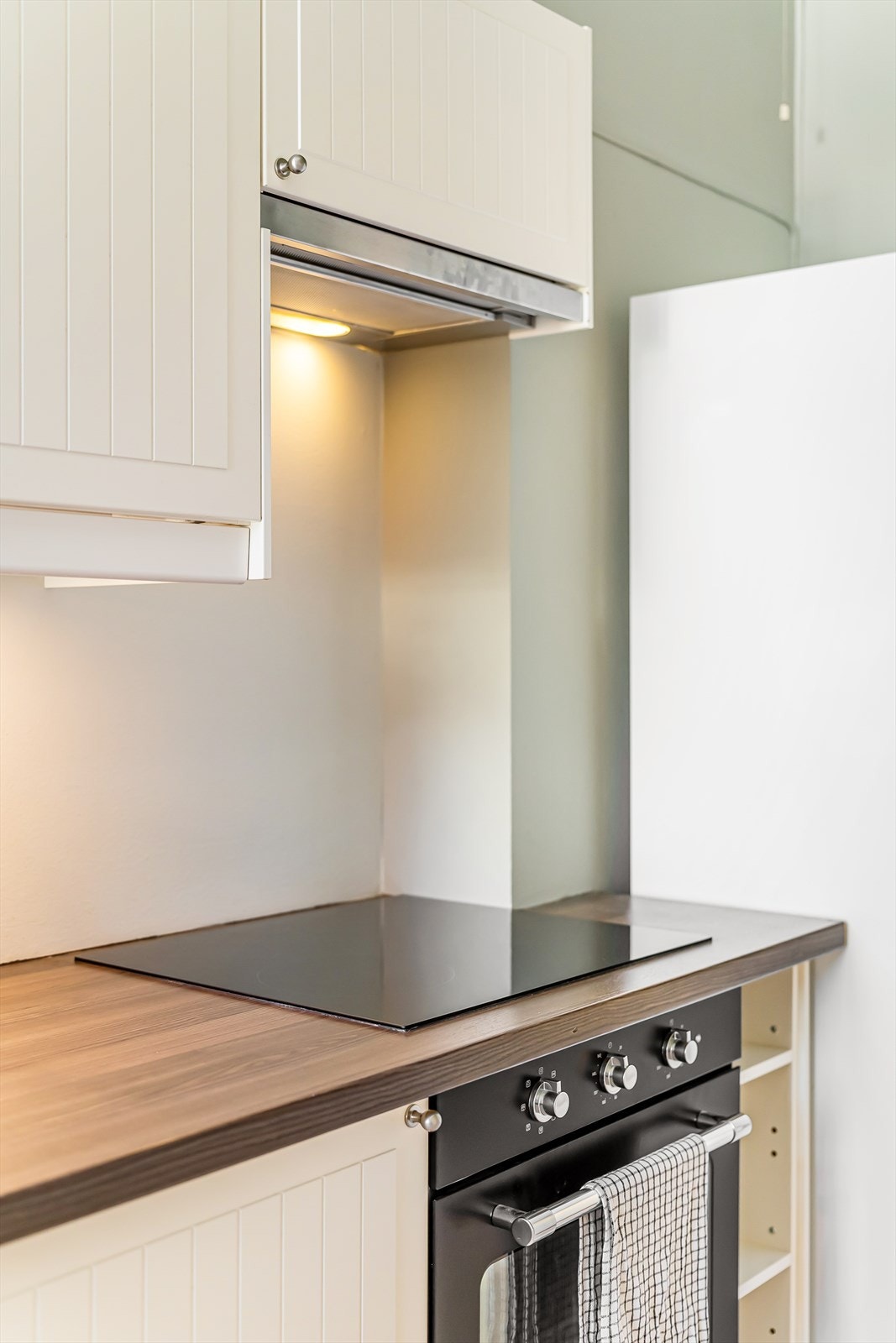 Integrerte hvitevarer som koketopp, stekeovn og oppvaskmaskin på kjøkkenet. Det er opplegg for vaskemaskin. Galleribilde