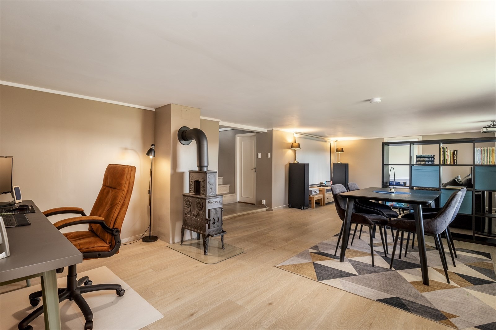 Den delikate kjellerstuen har moderne overflater med enstavs laminat på gulvet og slette, malte plater på veggene. Sentralt i rommet er det vedovn med vakre detaljer og glassplate under. Galleribilde