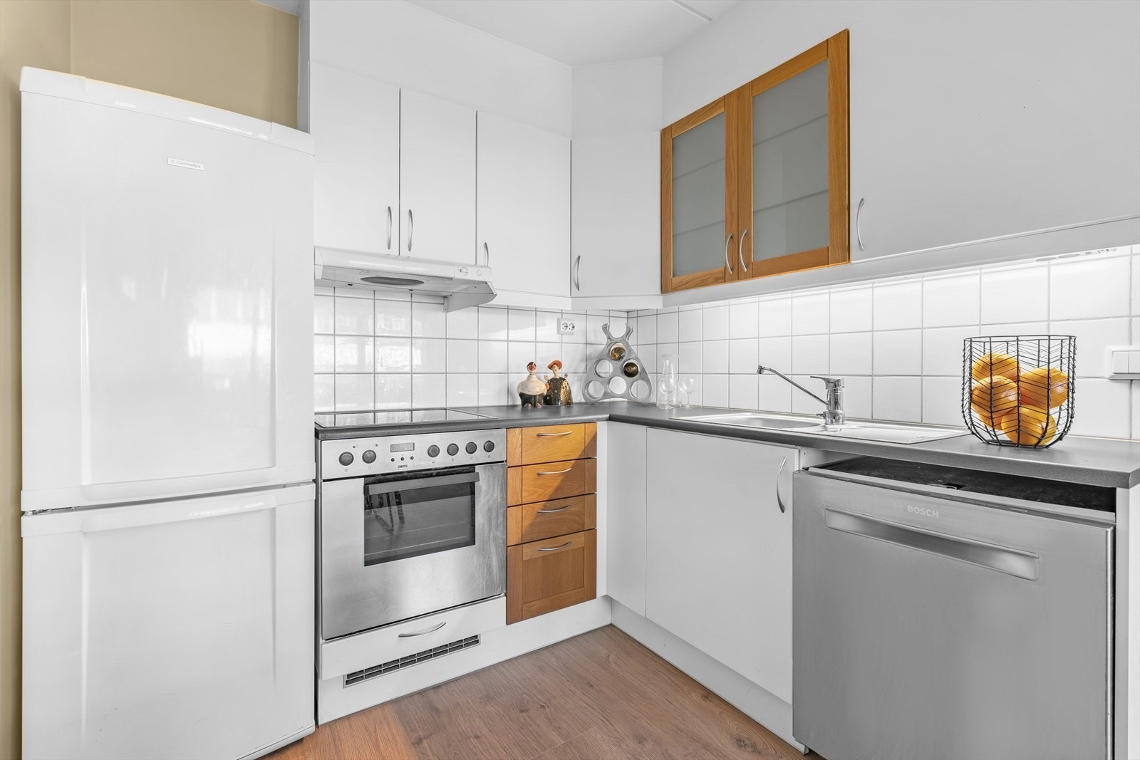 Kjøkken med delvis integrerte hvitevarer. Det er laminat benkeplate og fliser over benk Galleribilde