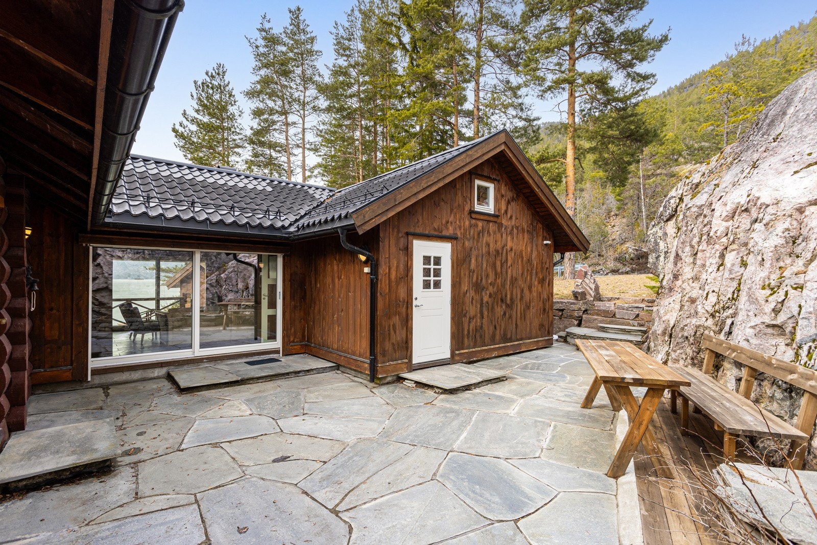Koselig uteområde med skiferstein. Fritidsboligen har en gjennomtenkt planløsning med to innganger på hver ende av hytta. Galleribilde