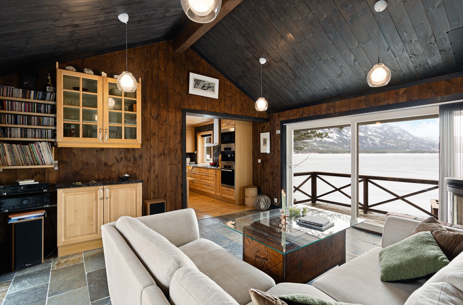 Stuen har fliser på gulv og er innredet med sofagruppe og vedovn. Galleribilde