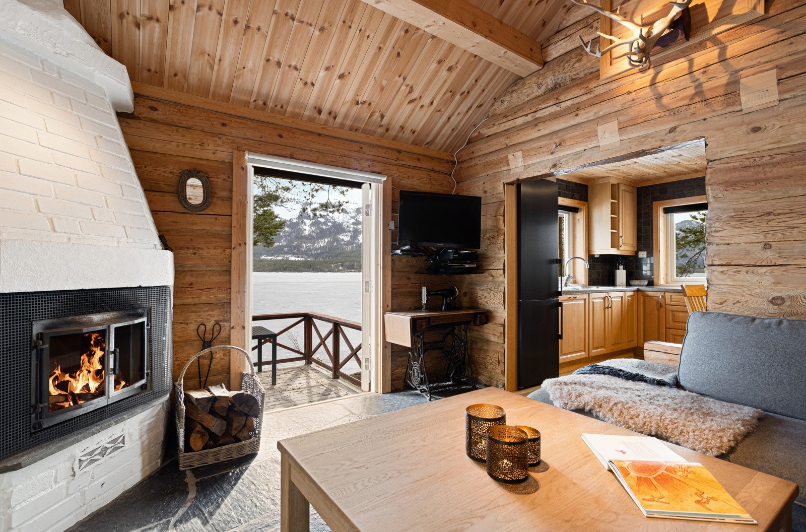 Stuen er innredet med sofagruppe, stor, åpen peis og har utgang til terrasse/uteområde. Galleribilde