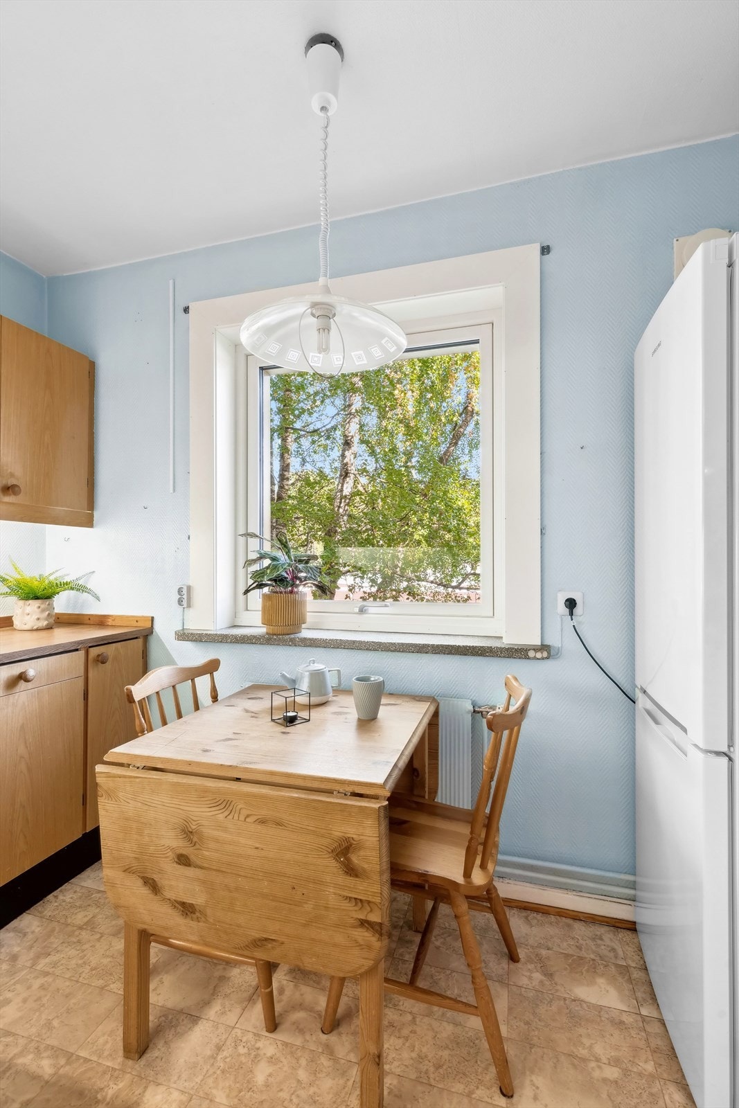 Eldre kjøkkeninnredning med glatte fronter, belysning under overskap og laminat benkeplate med nedfelt kum i stål. Galleribilde