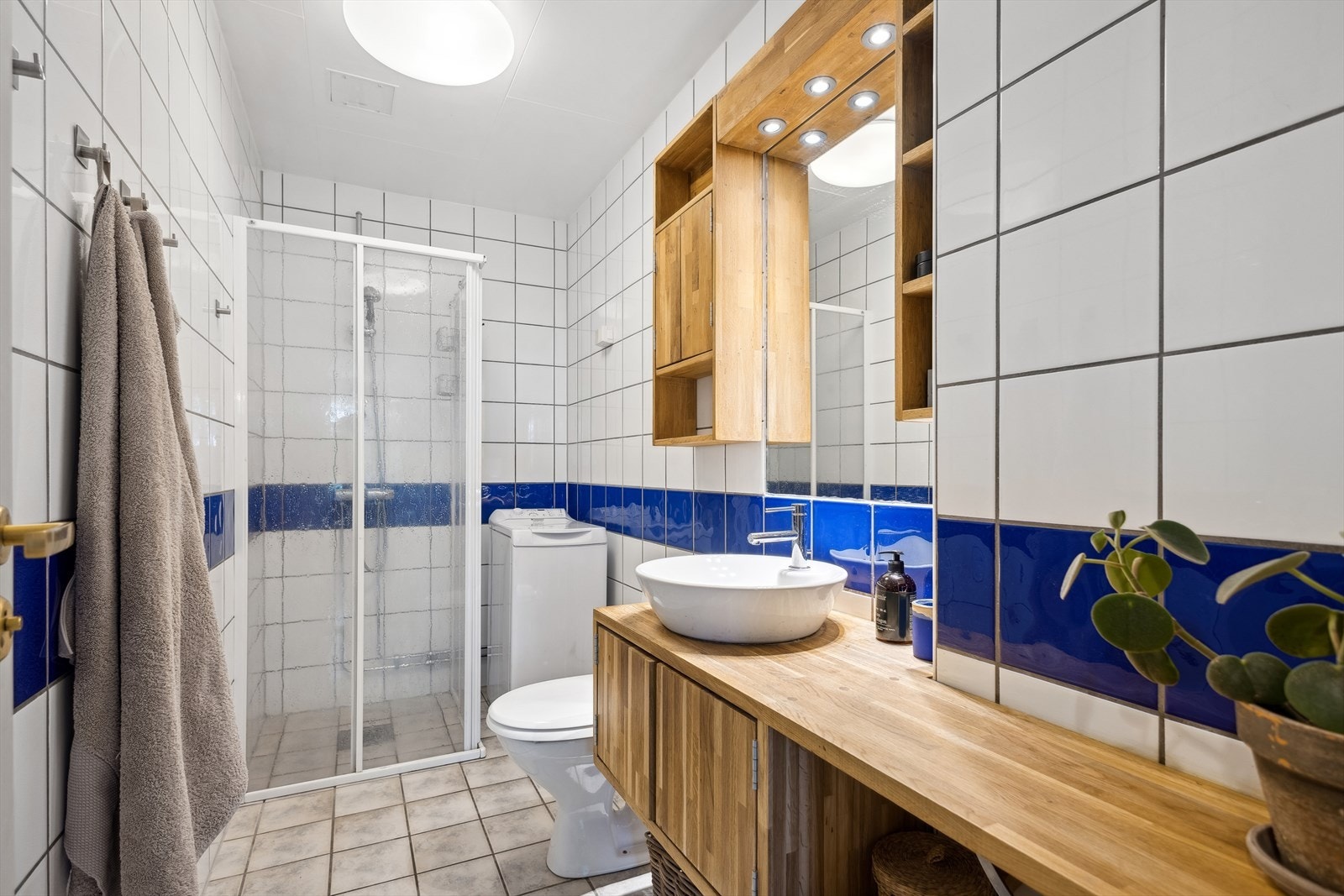 Badet er flislagt og utstyrt med varmekabler og har en stilren innredning med servant, underskap og speil med integrert belysning. Det er også opplegg for vaskemaskin. Galleribilde